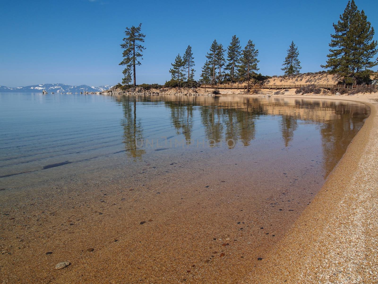 Scenic view of beautiful Lake Tahoe in Spring, landscape of the United States of America, clear water, nice sky, stone island, tree, fresh air and snow mountains