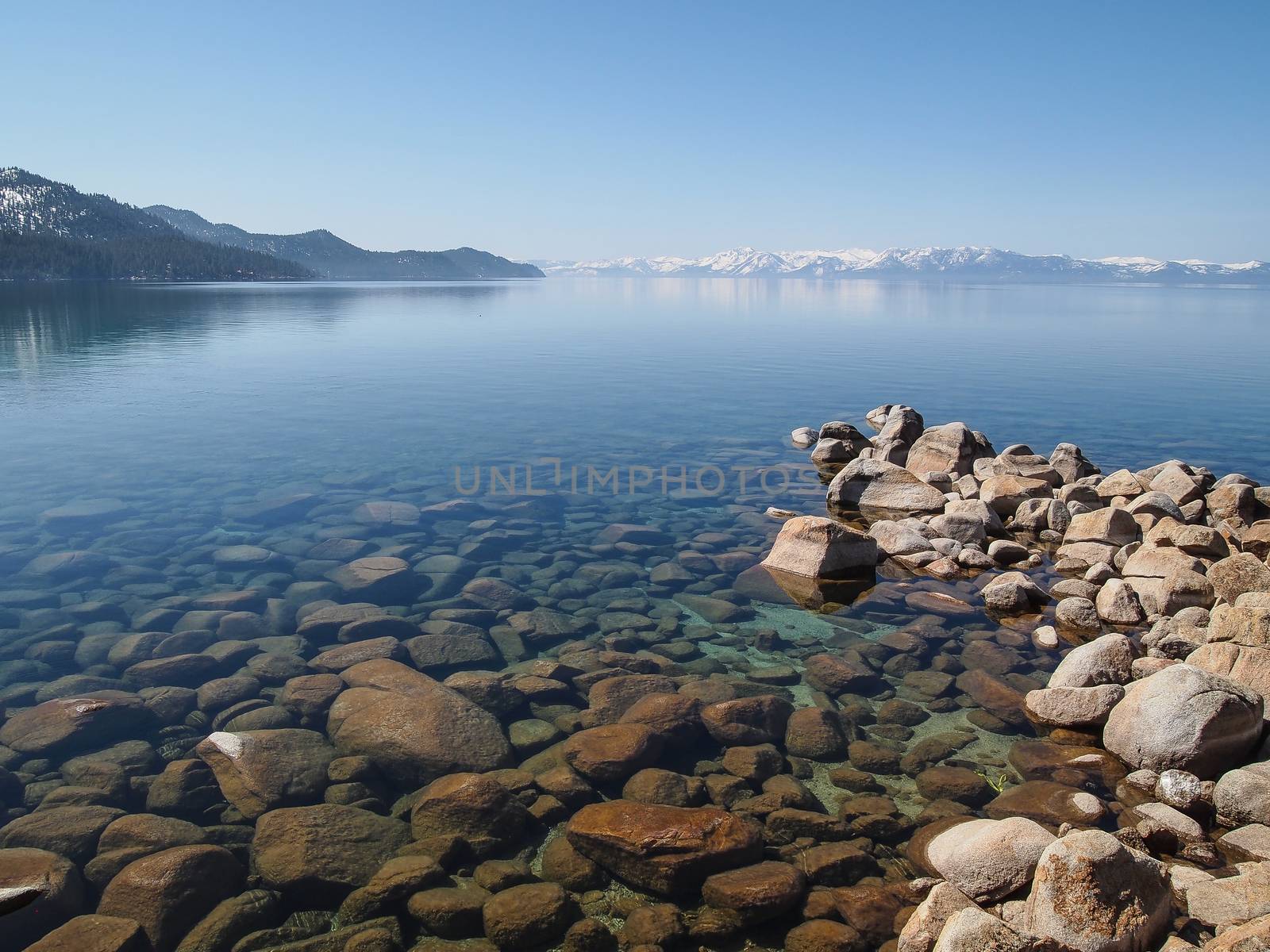 Scenic view of beautiful Lake Tahoe in Spring, landscape of the United States of America, clear water, nice sky, stone island, tree, fresh air and snow mountains