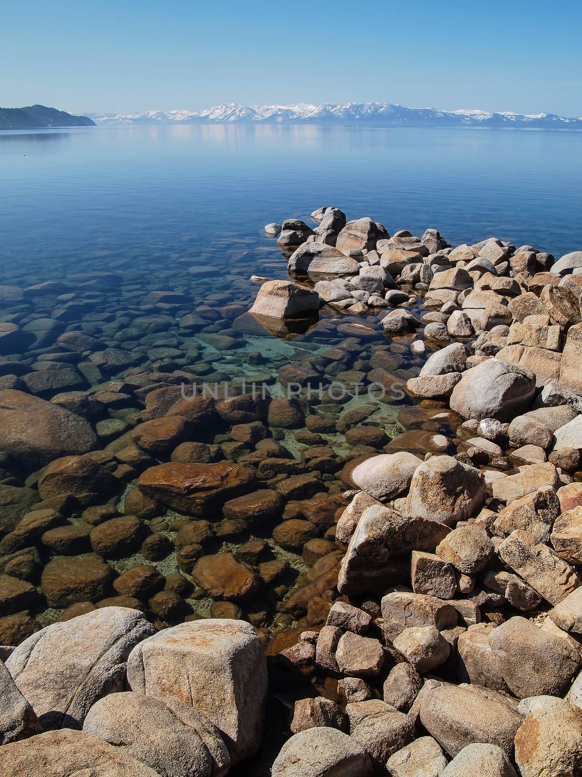 Scenic view of beautiful Lake Tahoe in Spring, landscape of the United States of America, clear water, nice sky, stone island, tree, fresh air and snow mountains