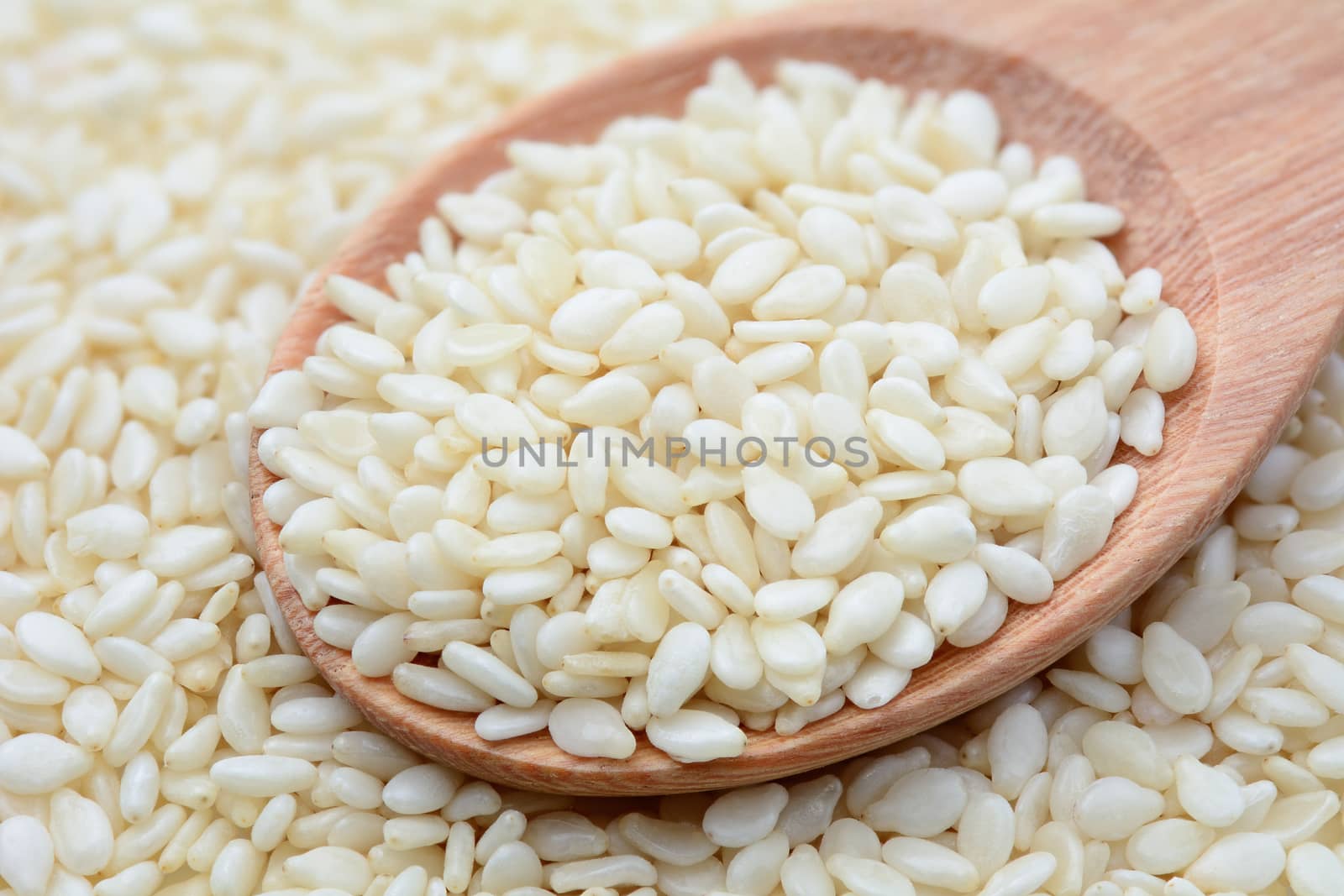 Closeup of white sesame seeds in wooden spoon