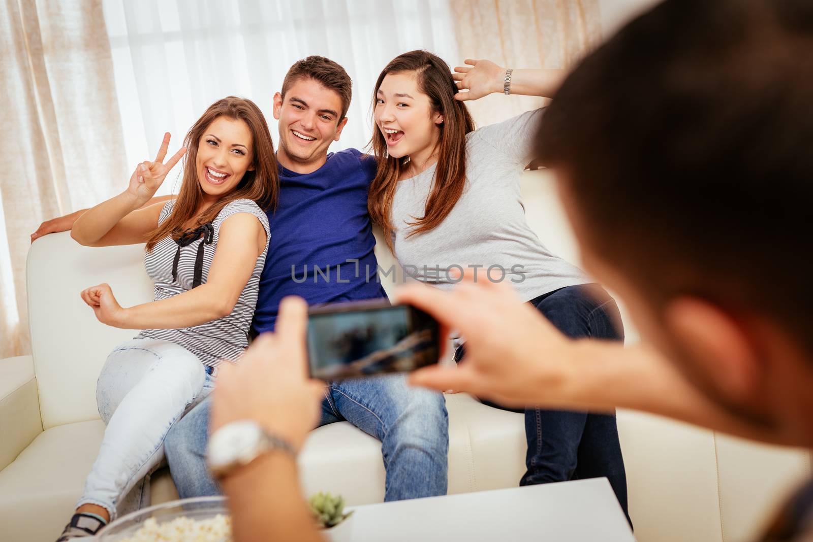 Four cheerful best friends having nice time in an apartment and taking a photo of themselves.