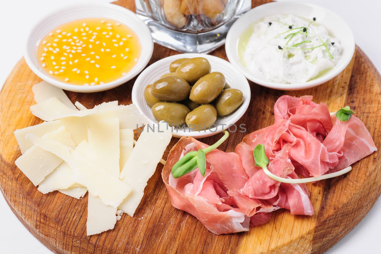 Assorted cheeses, wallnuts, prosciutto, green olives and other snacks served at wooden board