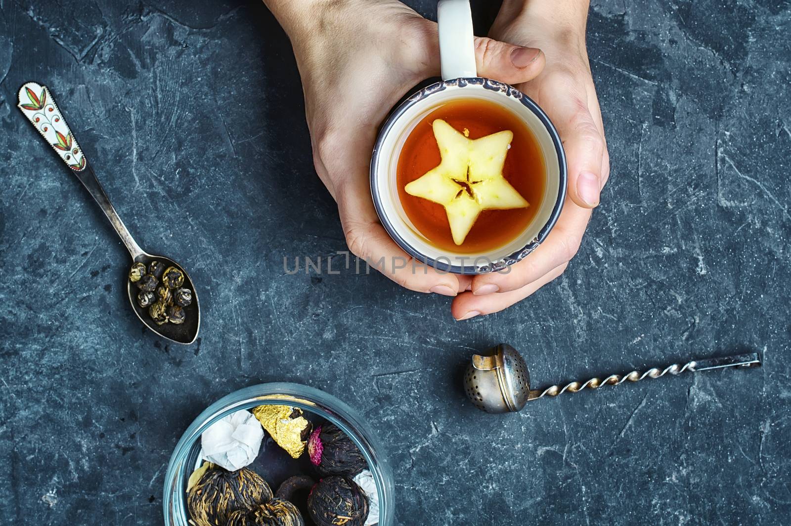 With warming mug of tea in hand on blue slate background