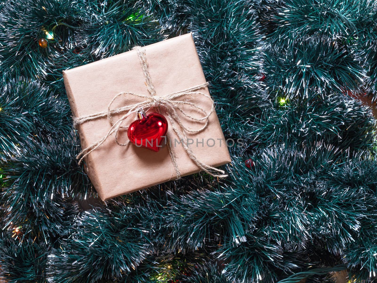 Christmas gift box on a fur-tree and garland background. Packaging holiday gifts