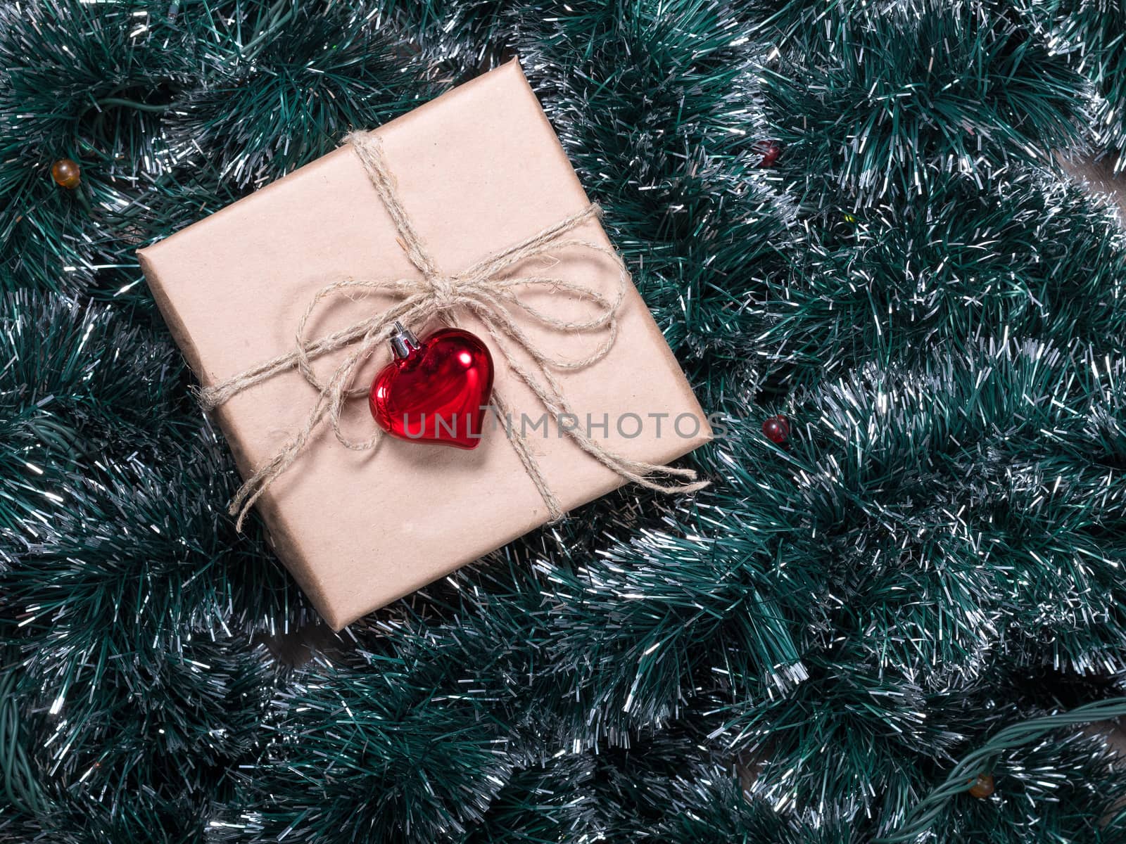 Christmas gift box on a fur-tree and garland background. Packaging holiday gifts