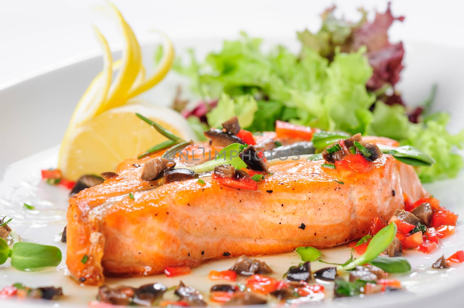 Roasted salmon steak with rosemary, lemon and lettuce, on white plate. Selective focus.