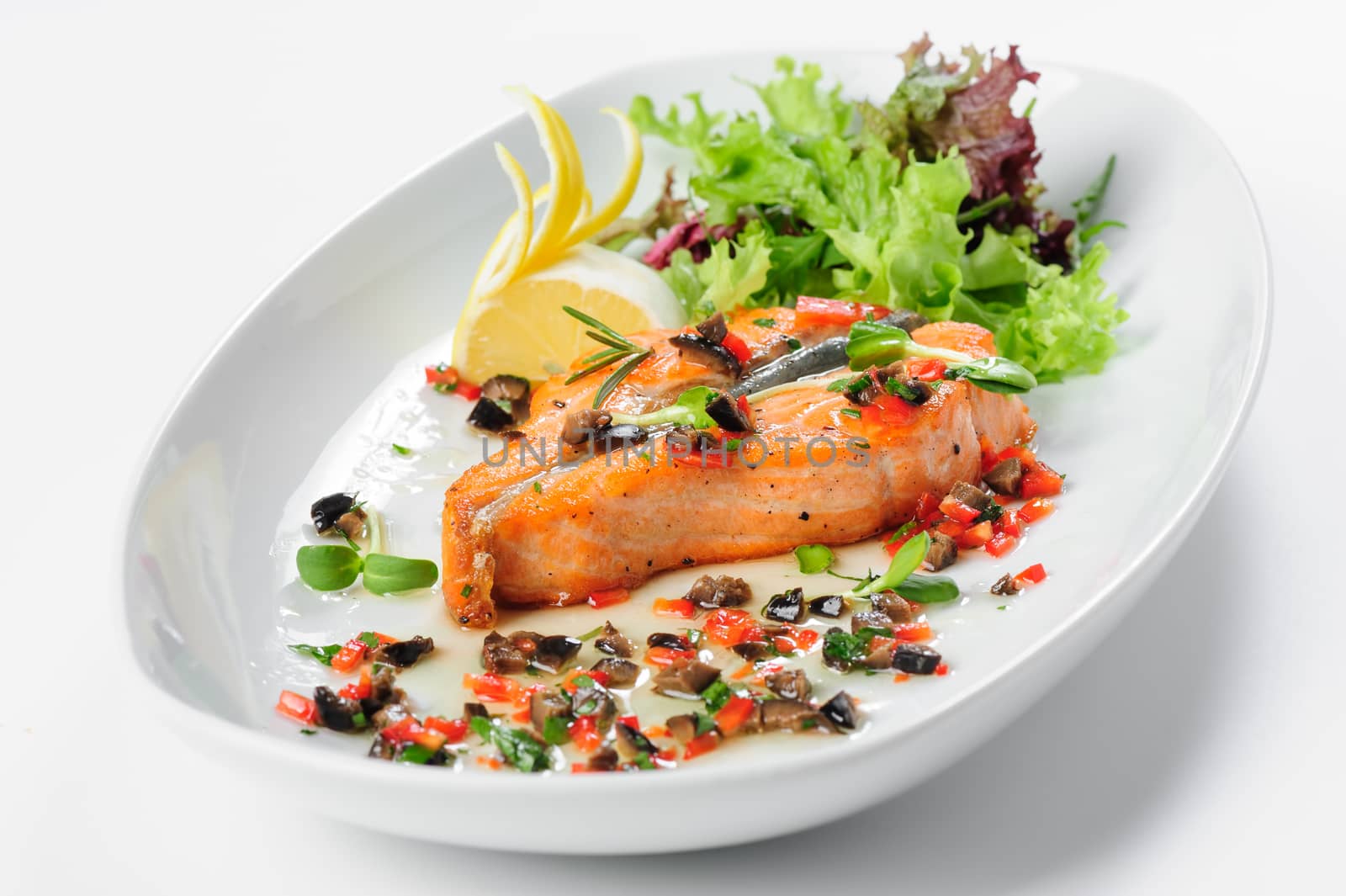 Roasted salmon steak with rosemary, lemon and lettuce, on white plate. Selective focus.
