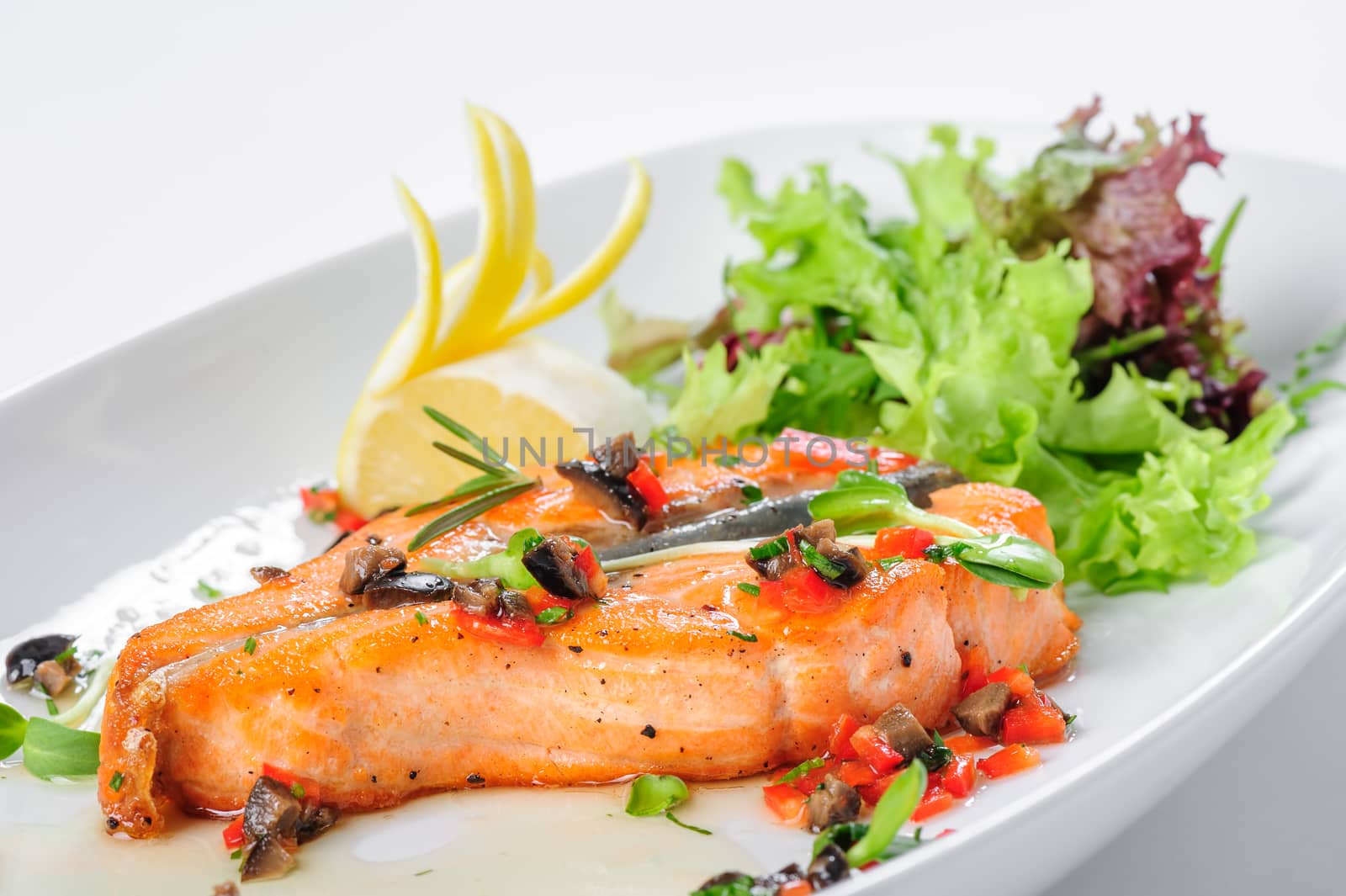 Roasted salmon steak with rosemary, lemon and lettuce, on white plate. Selective focus.