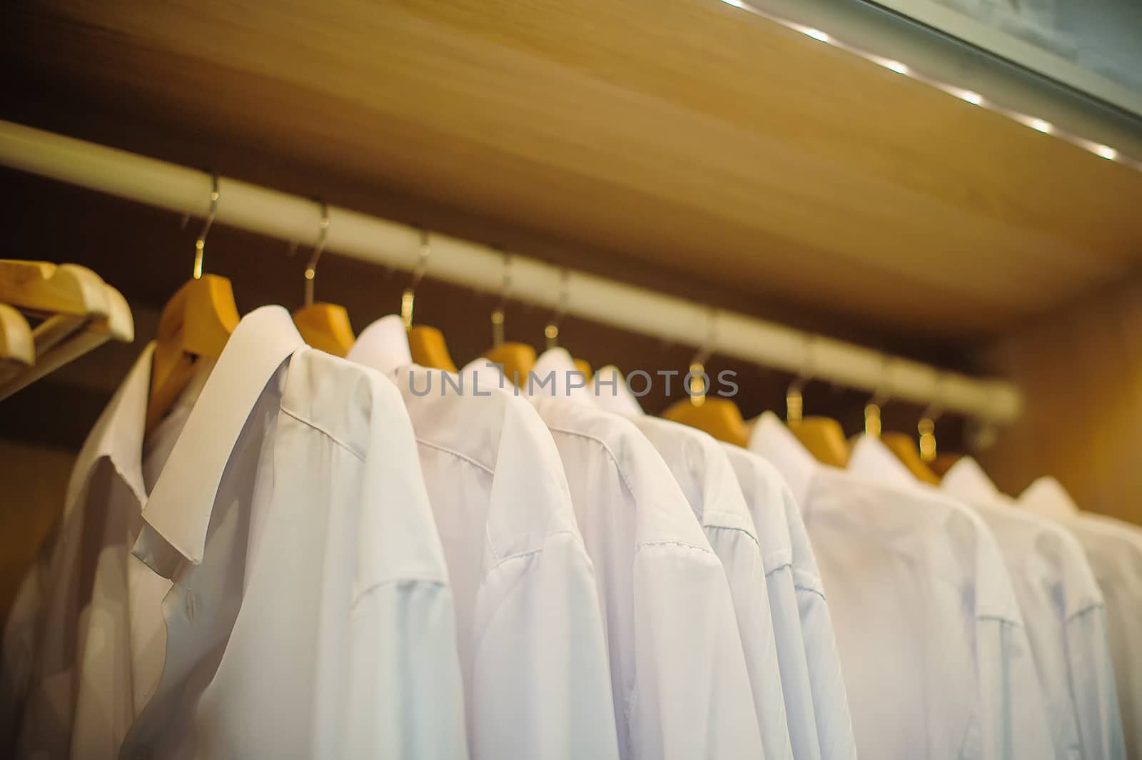 white mans shirts on hangers in store.