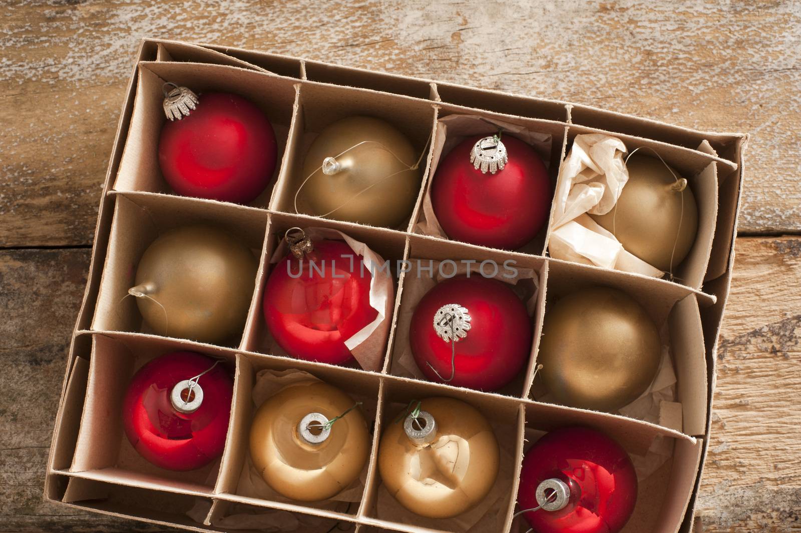 Cardboard carton of red and gold Christmas balls ready to decorate the house for the festive holiday season viewed from above on a rustic wood table