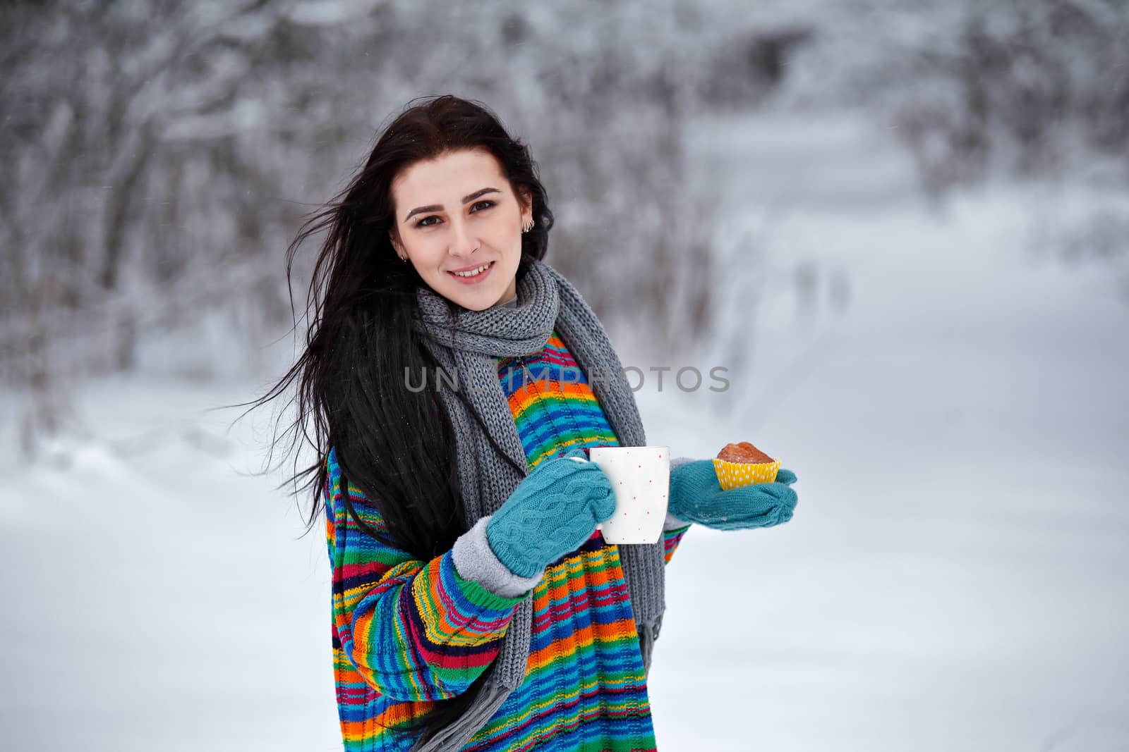 Beautiful young woman in a sweater. Winter outdoors walk with a cup of coffee