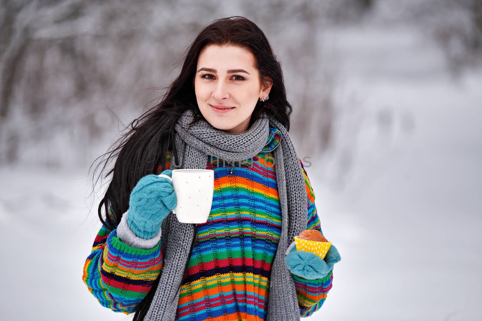 Beautiful young woman in a sweater. Winter outdoors walk with a cup of tea