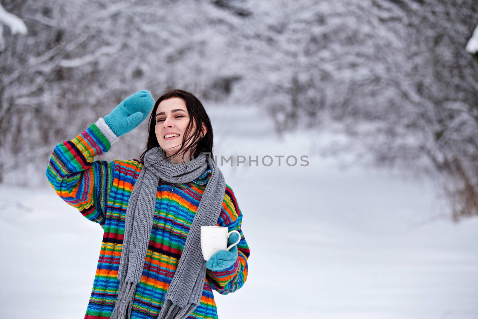 Beautiful young woman in a sweater. Winter outdoors walk with a cup of coffee