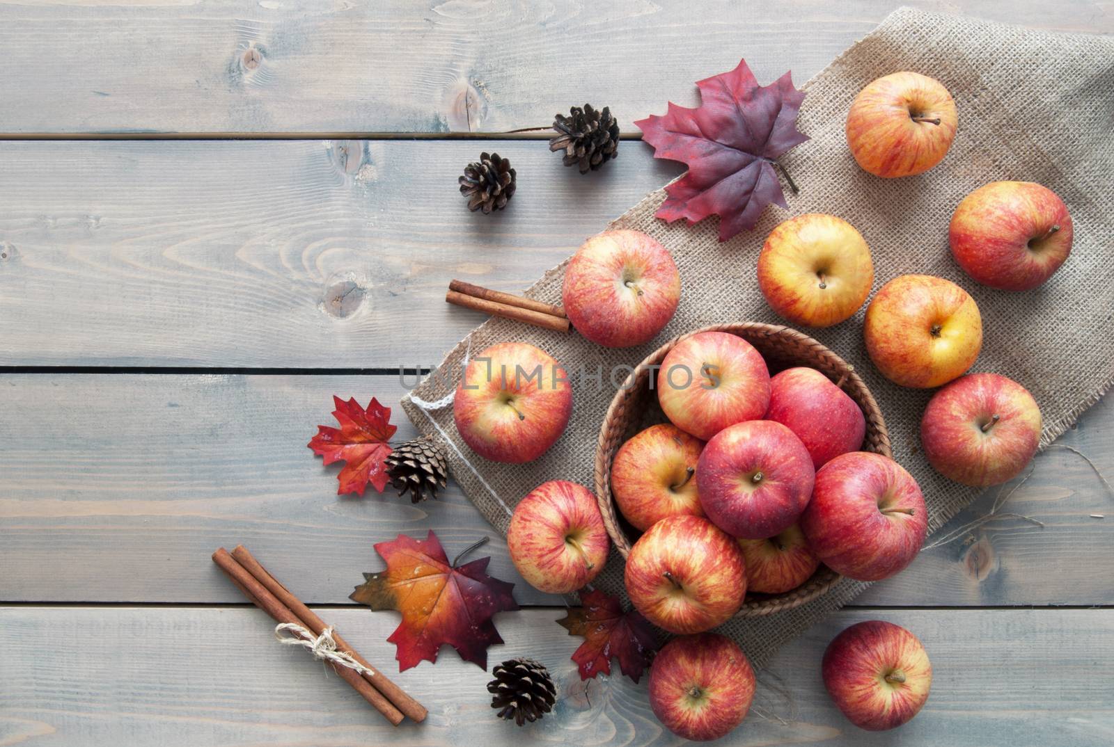 Autumn leaves with apples over a wooden background