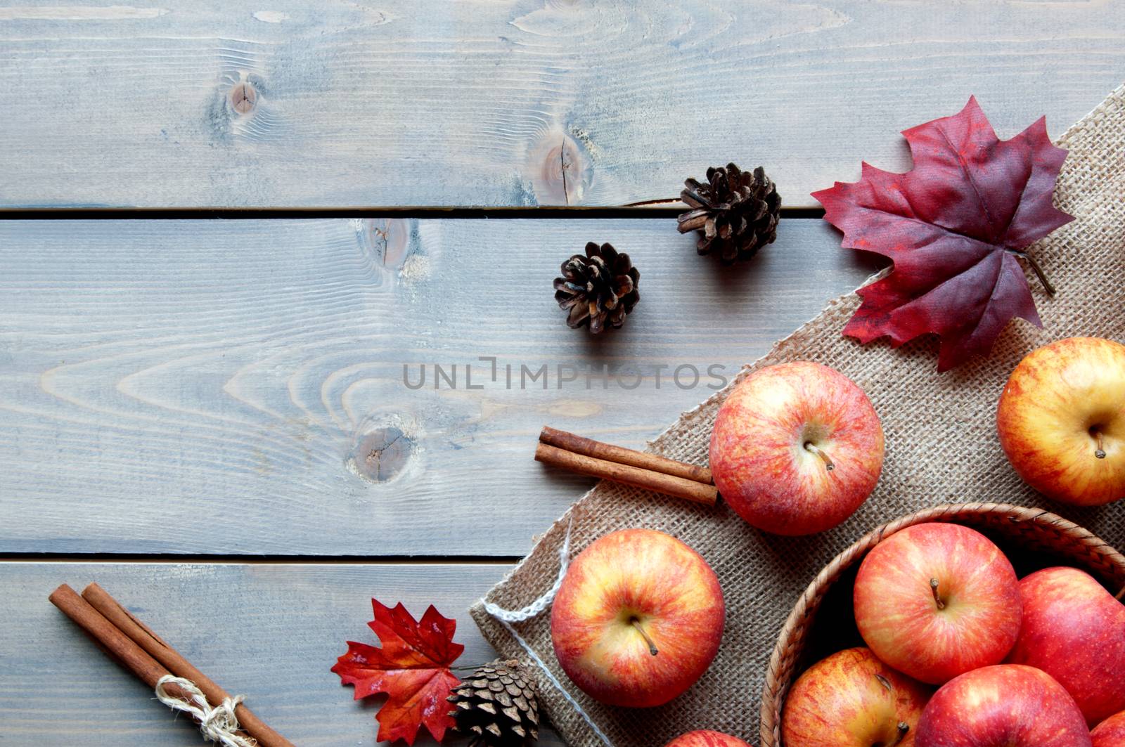 Autumn leaves with apples over a wooden background