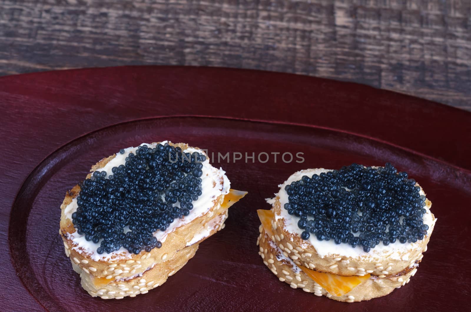 Sandwiches with black caviar on a wooden tray. Analog products.