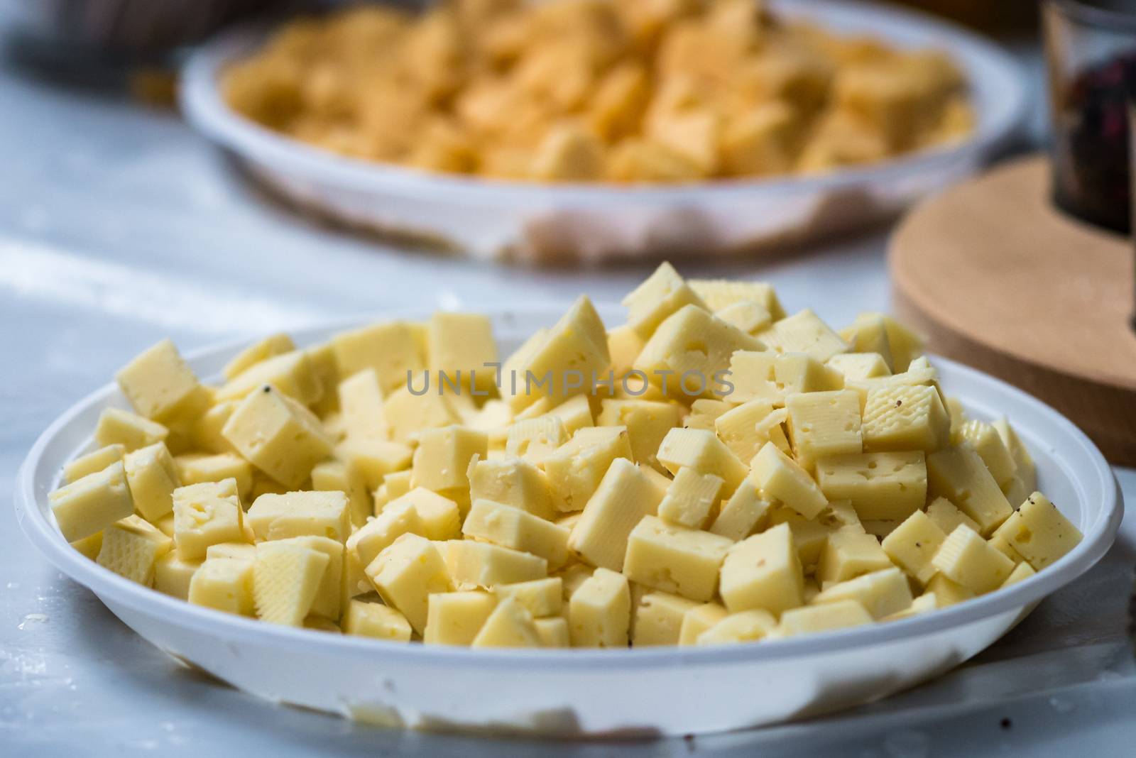 diced hard cheese on a white plastic plate at the exhibition