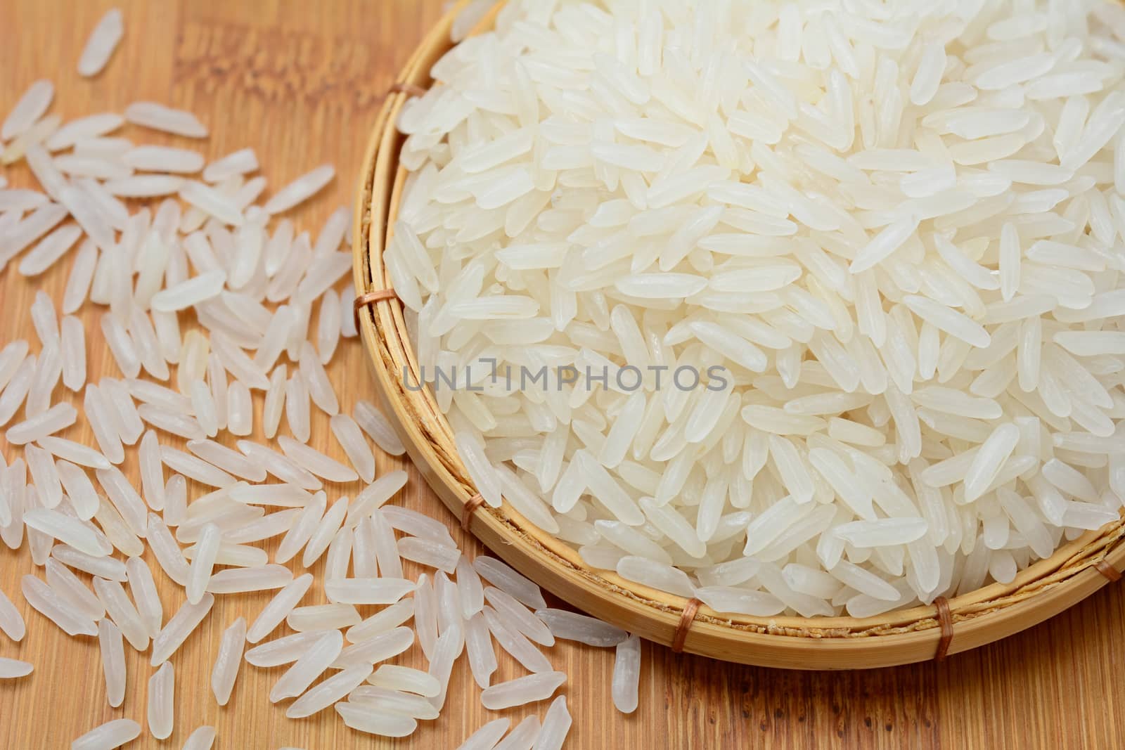 Closeup of Thai jasmine rice in bamboo basket and on wooden table