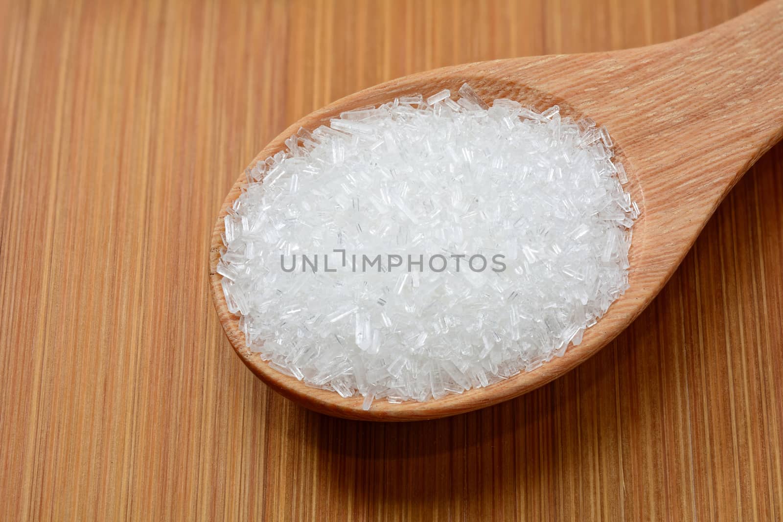 mono-sodium glutamate in wooden spoon and on wooden table