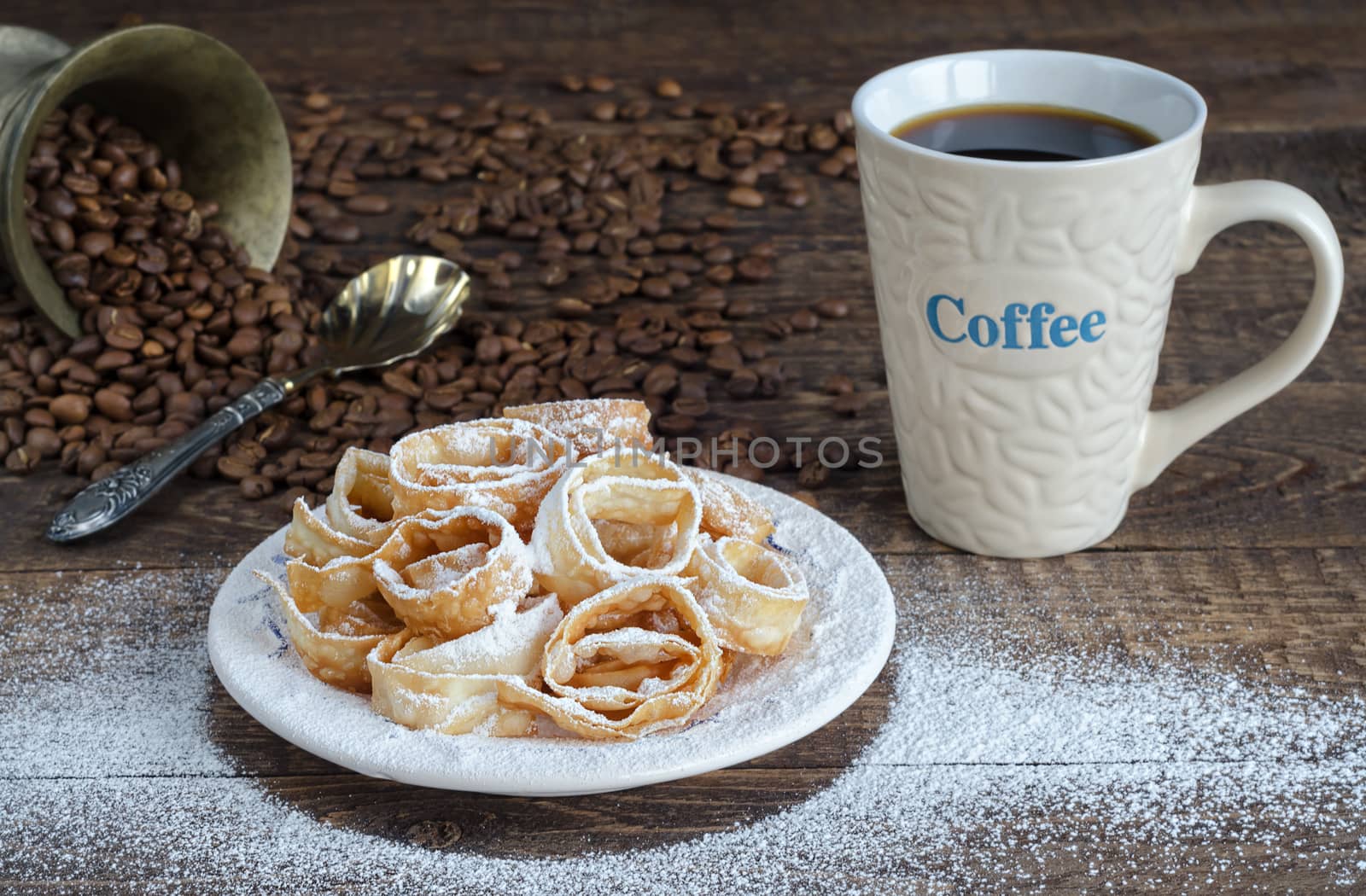 Crumbly cookies in powdered sugar and a Cup of coffee. Refried beans and spoon on a wooden surface.