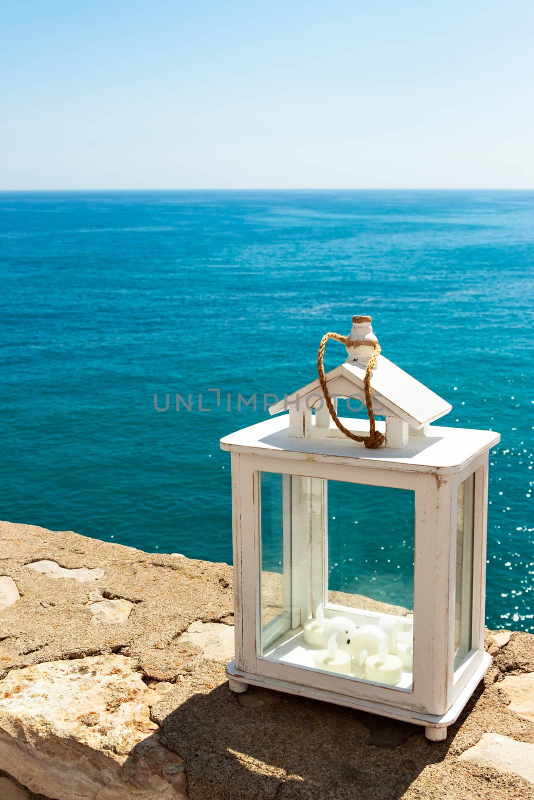 White lantern with the sea in the background. Vertical image.