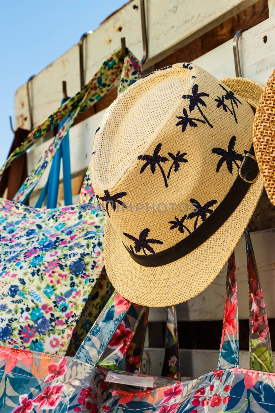 Straw hat with drawings of palm trees in a summer market. Vertical image.