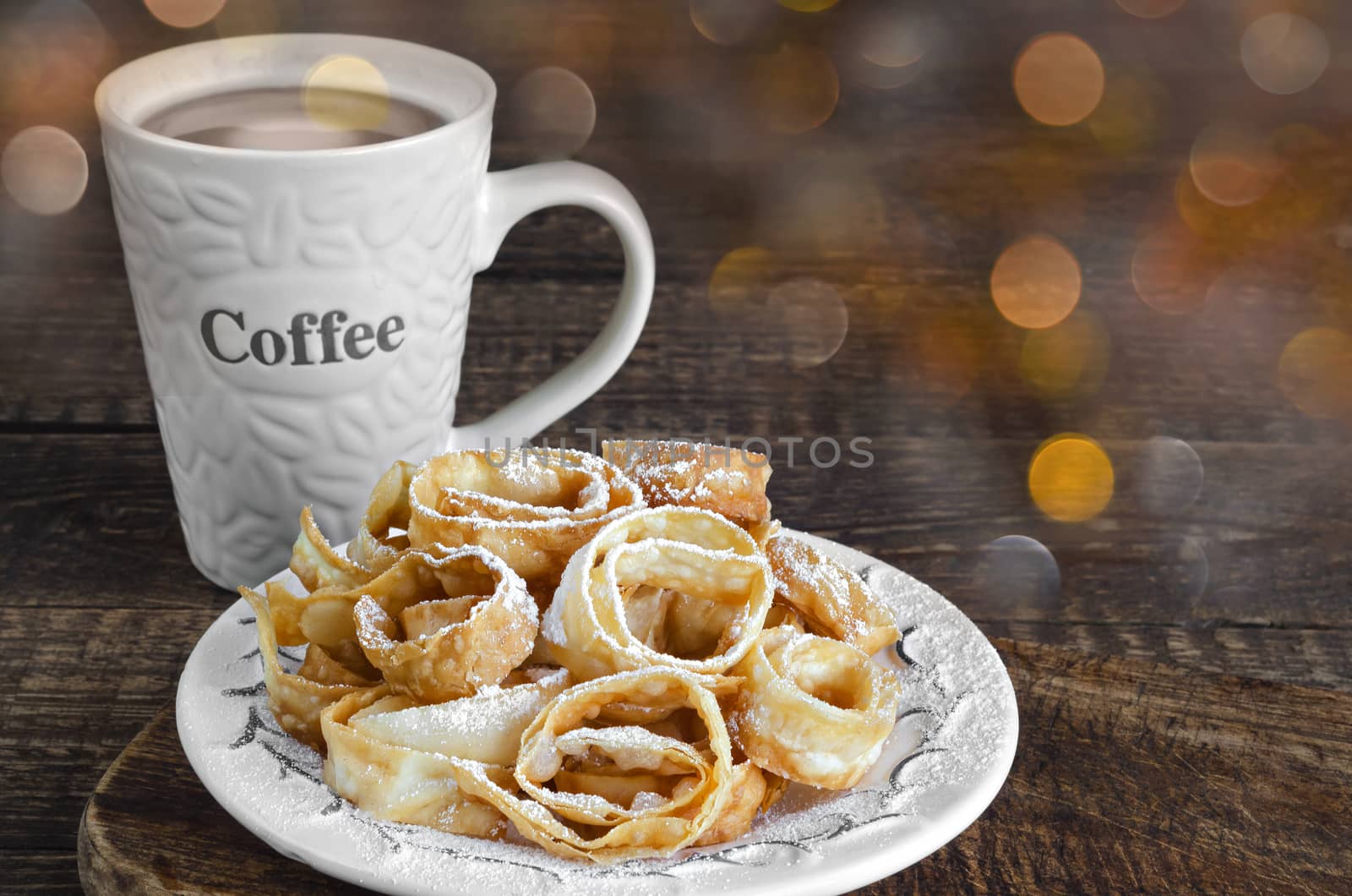 Crumbly cookies in powdered sugar and a Cup of coffee on wooden background. Colorful bokeh.