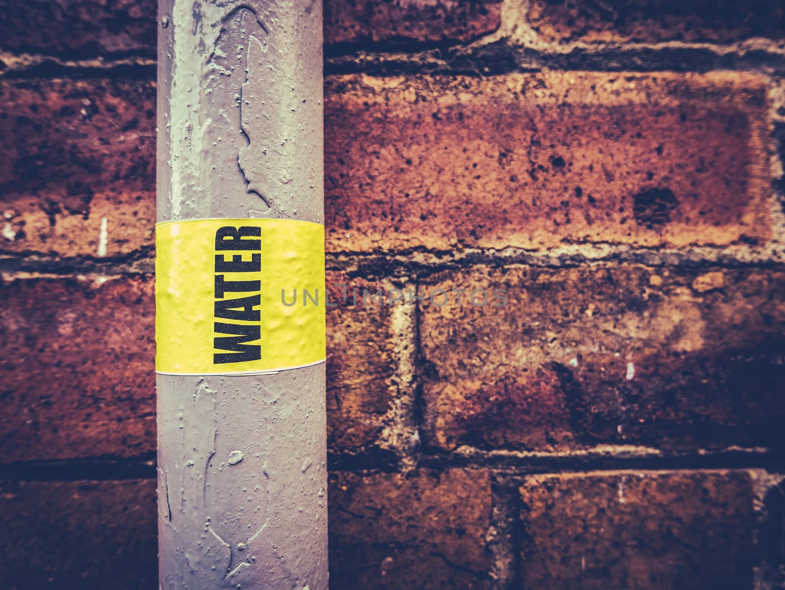 Detail Of An External Residential Water Pipe Against A Red Brick Wall