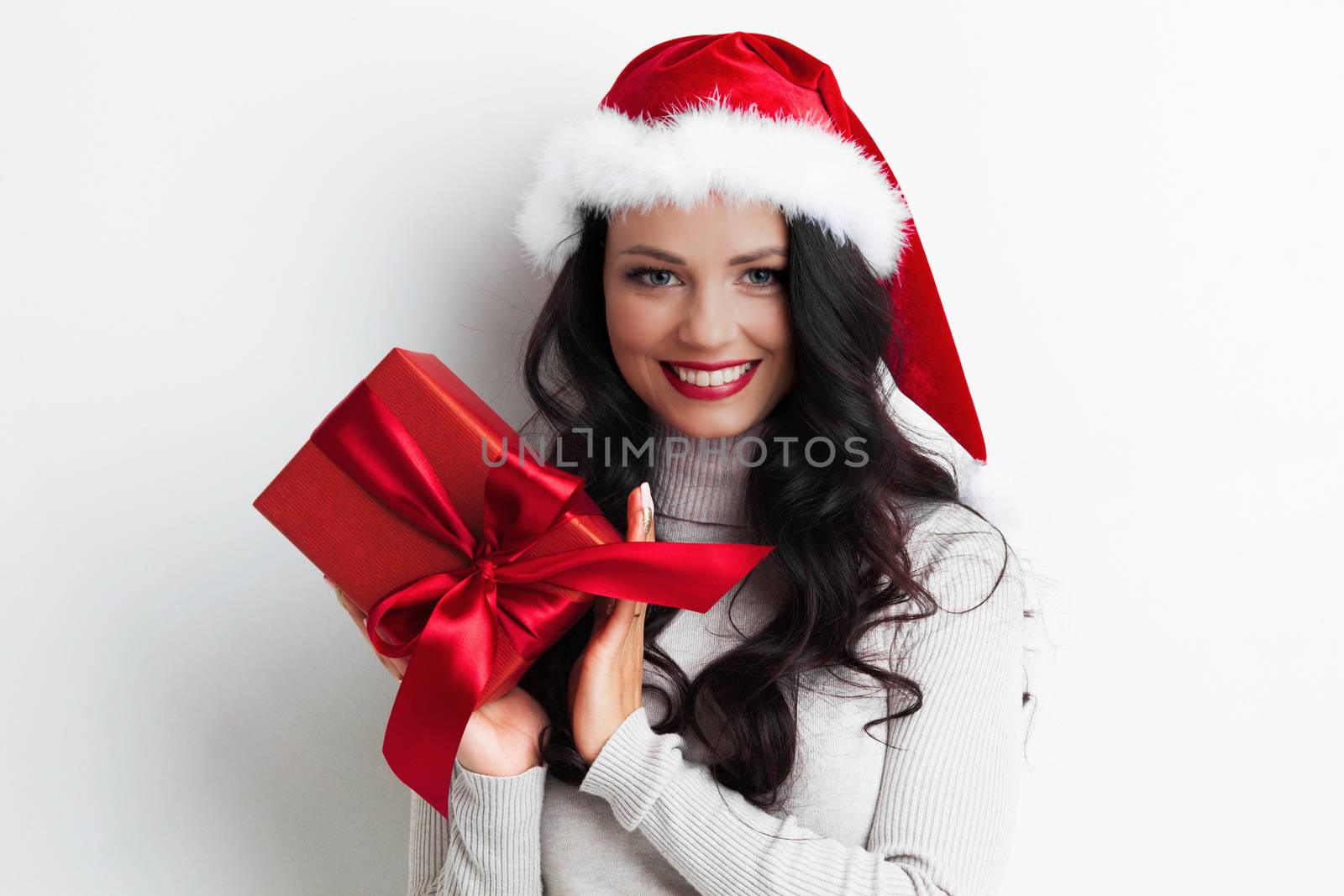 Young happy woman in santa hat holding christmas gift box