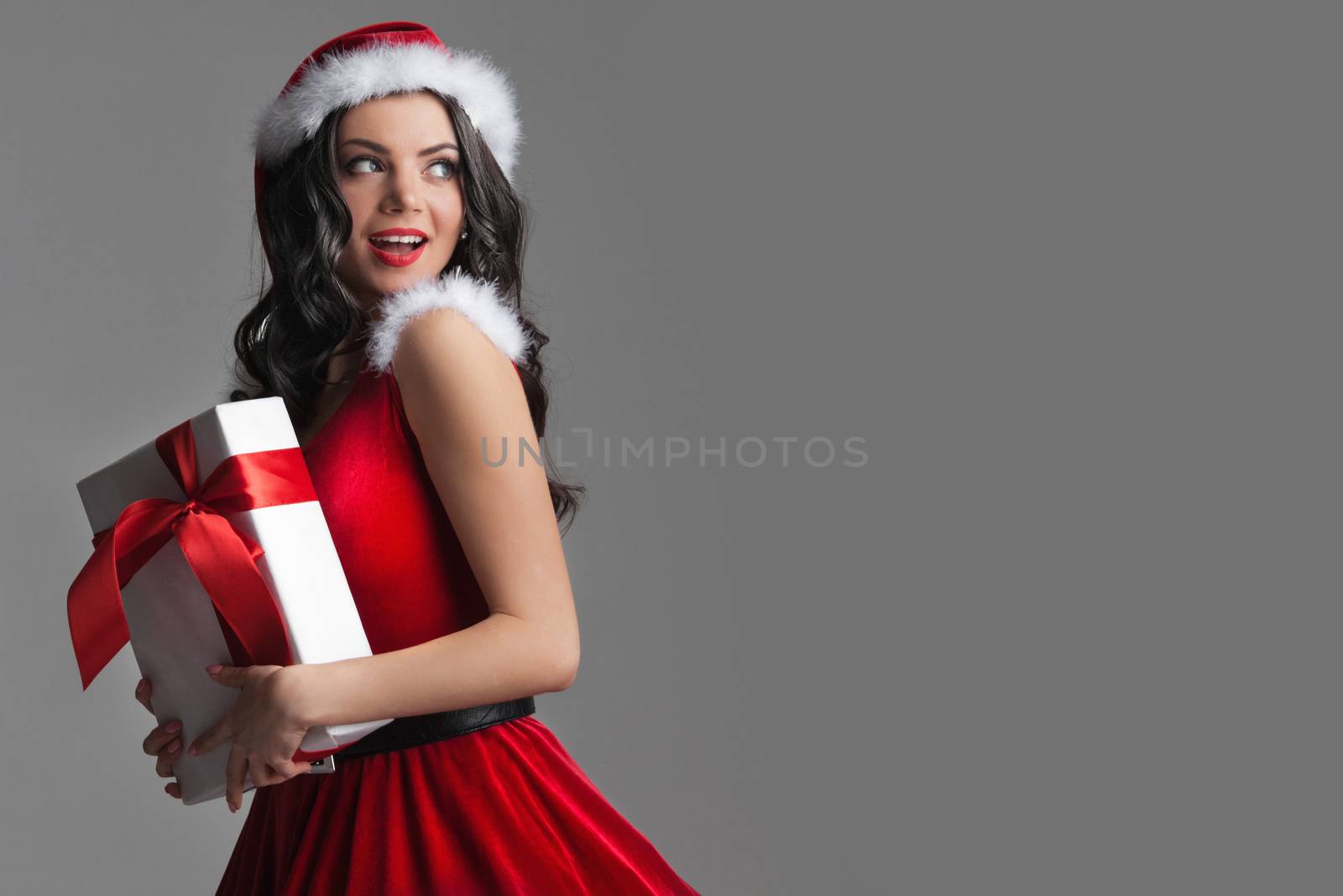 Excited surprised woman in red santa claus outfit holding Christmas present
