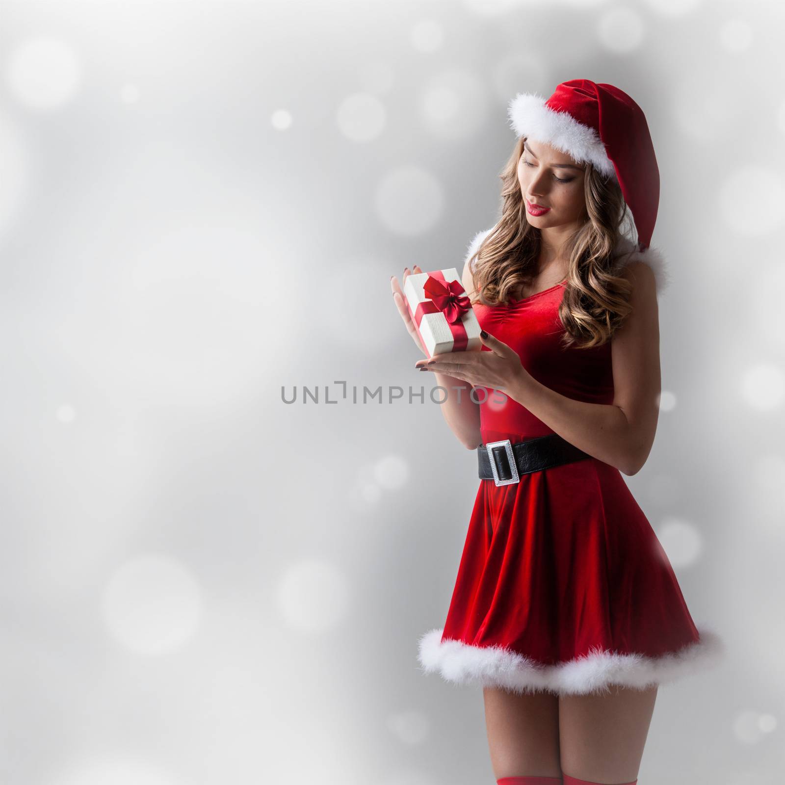 Beautiful hispanic woman in red santa claus costume holding Christmas gift