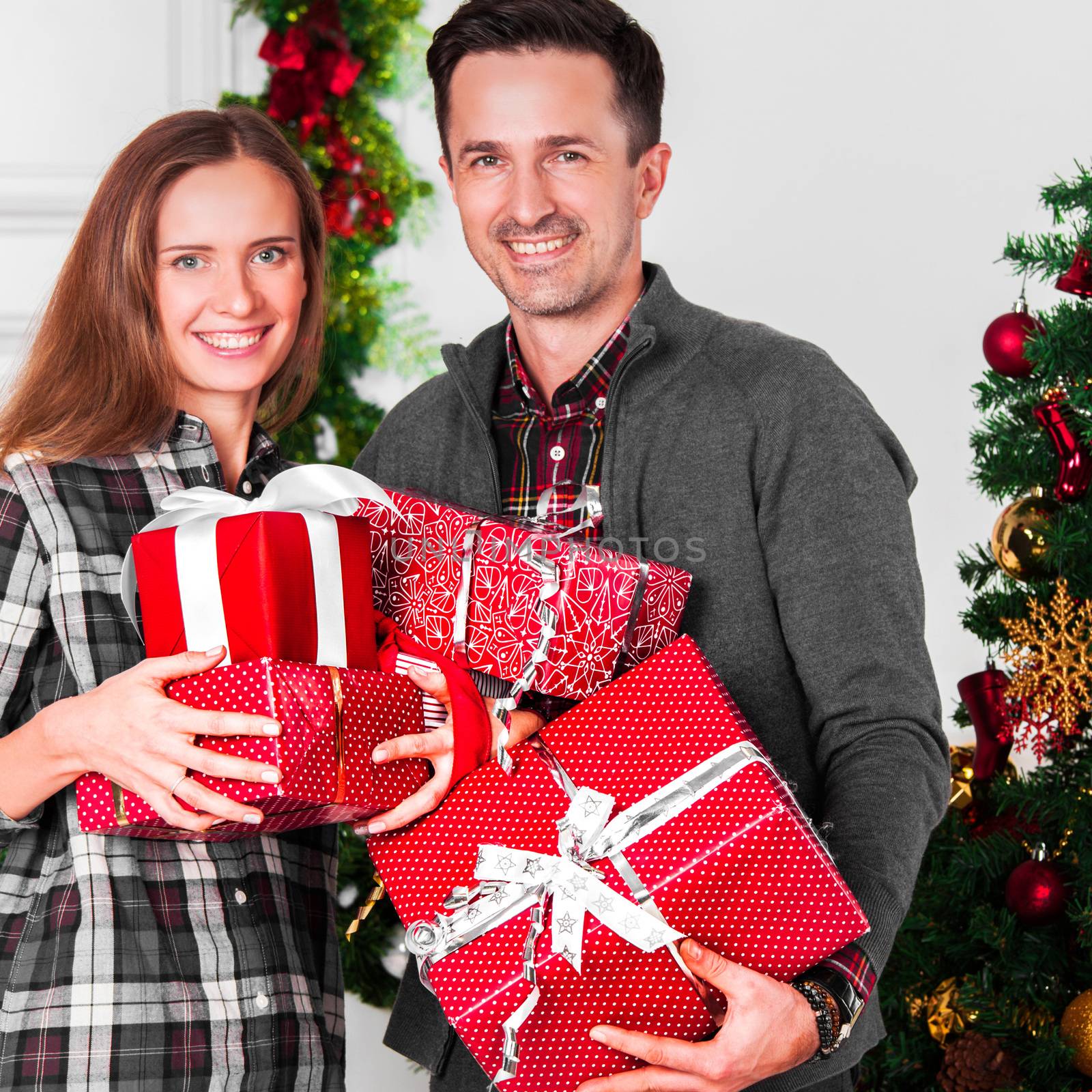 Happy couple with christmas gifts near decorated tree