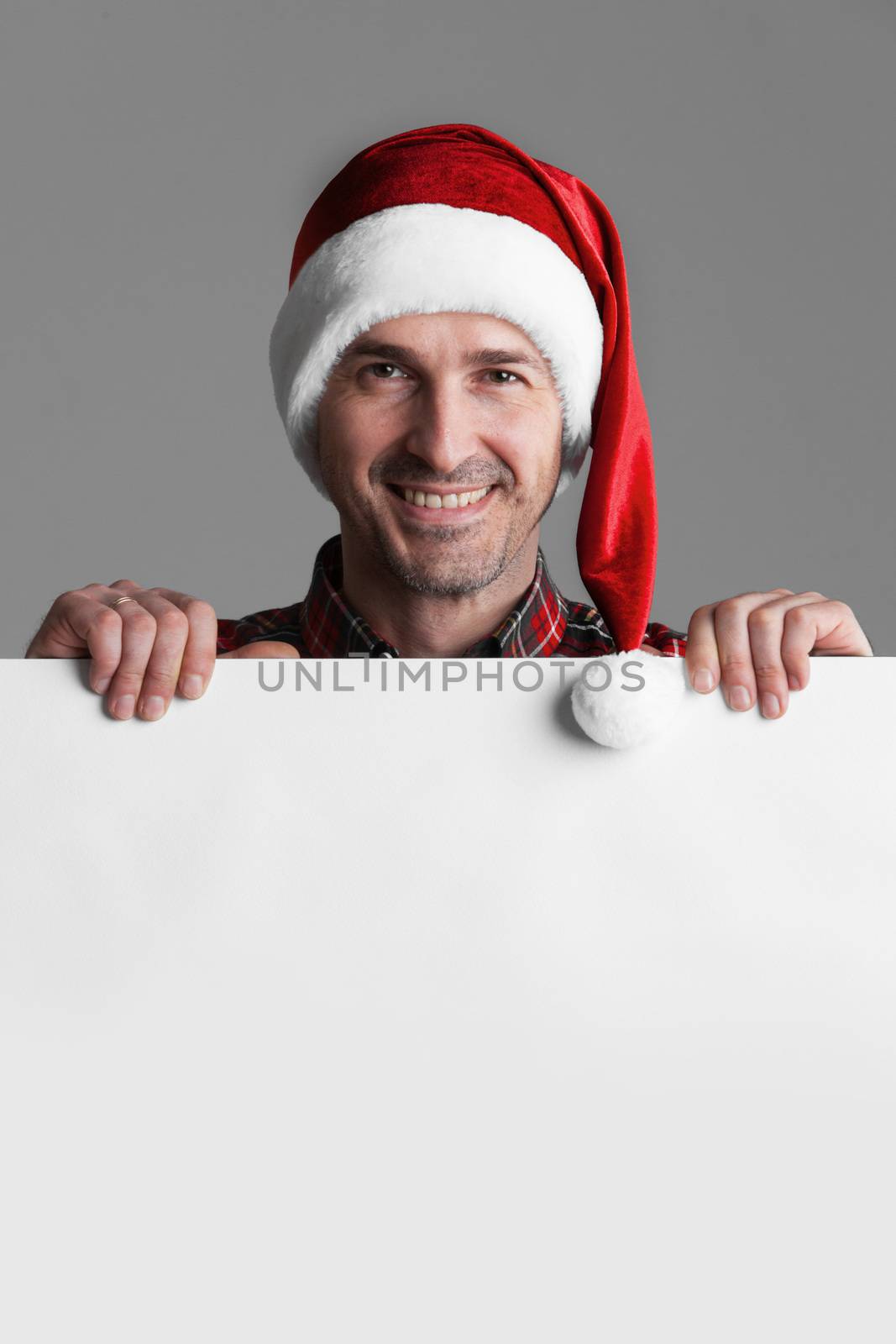 Happy smiling man in Santa's hat with white blank banner with copy space