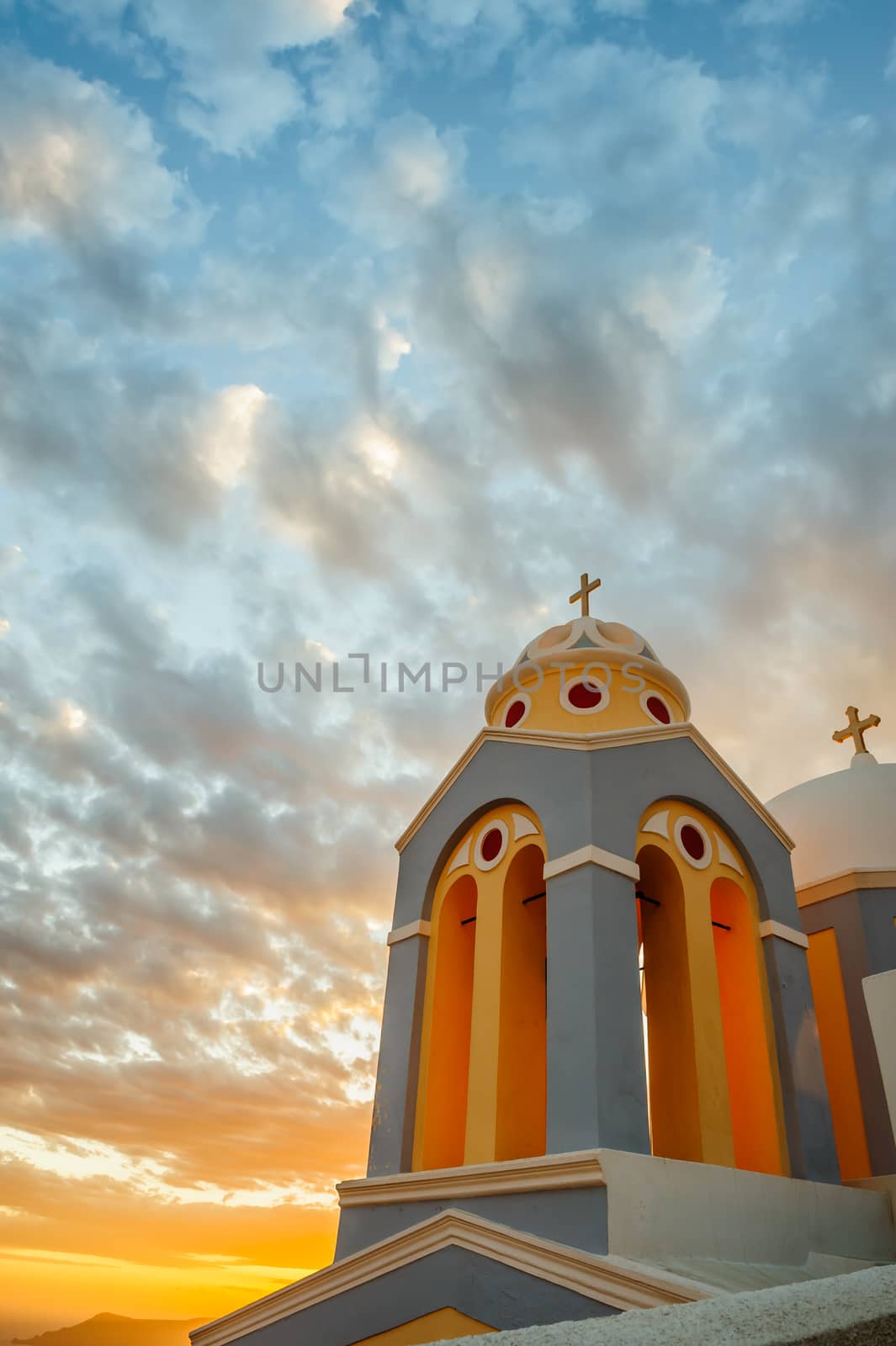 Orthodox church in rays of beautiful sunset. Fira, Santorini Greece. Copyspace