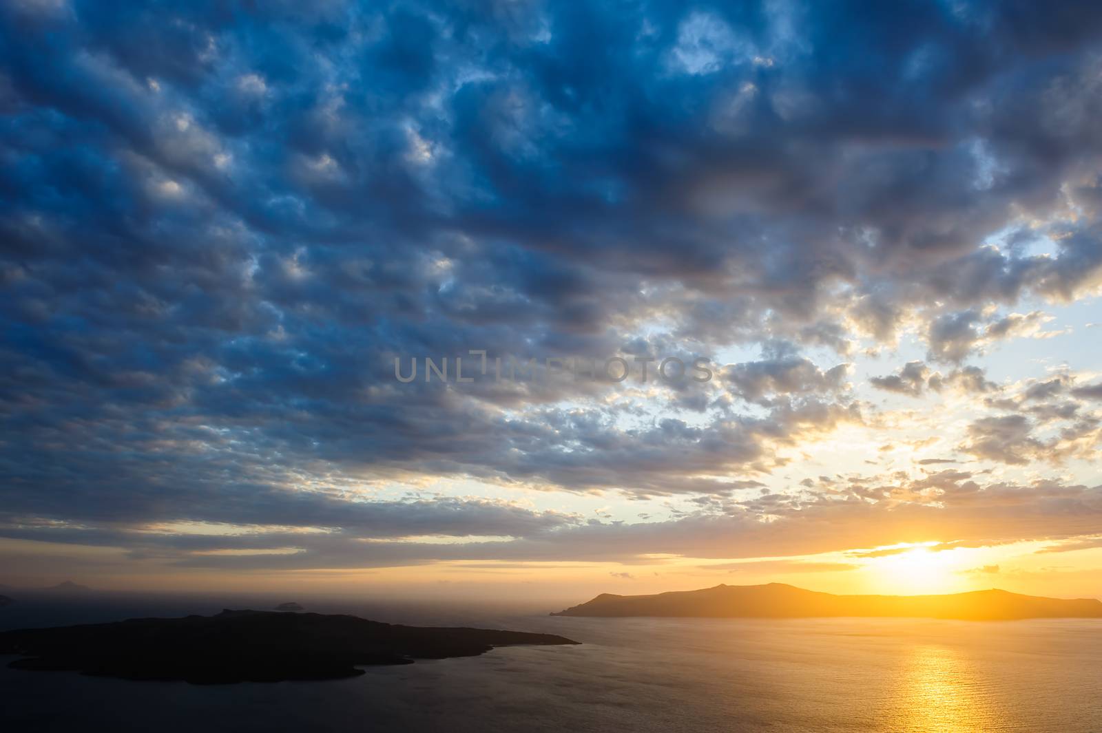 Dramatic sunset over Santorini caldera sea with volcano island