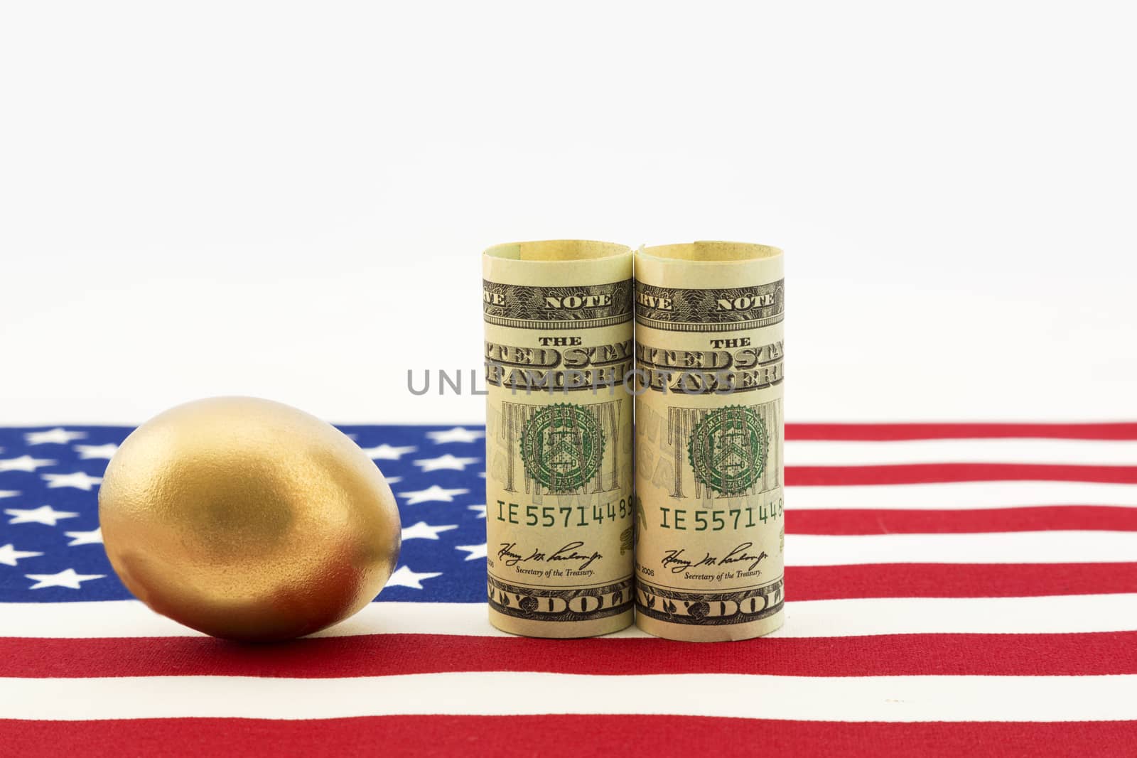 Gold nest egg with pair of American dollars placed on USA flag show success of national government policy and nation's business strength.  Horizontal image with copy space.  