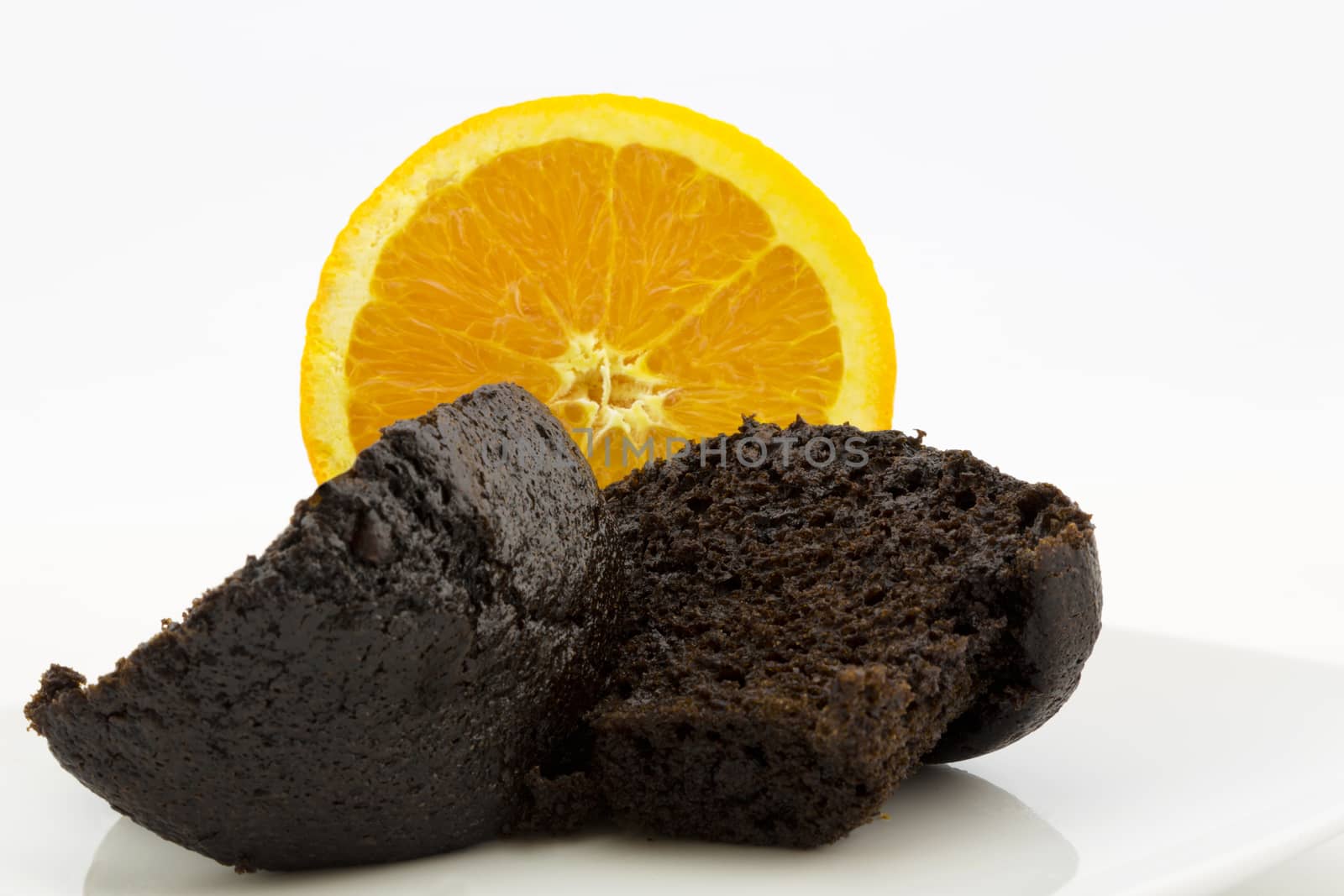 Sweet but healthy breakfast shown in fresh, hot chocolate muffin placed in front of sliced, juicy orange.  