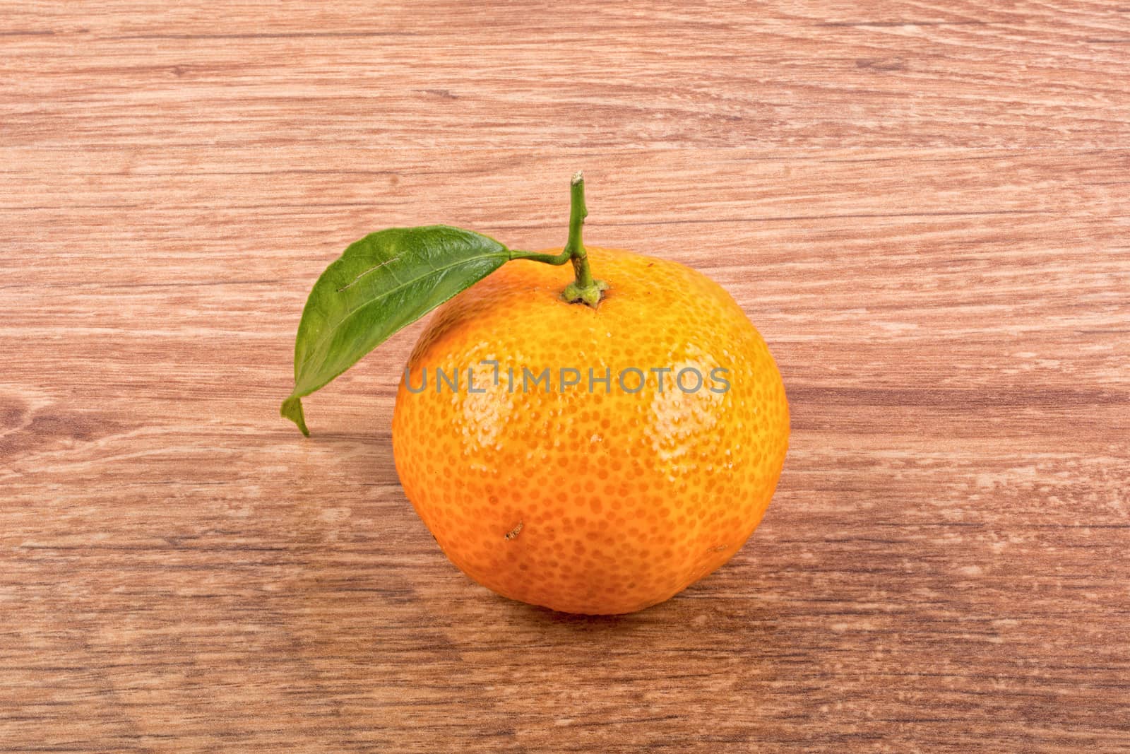Mandarin with leafs over brown wooden background