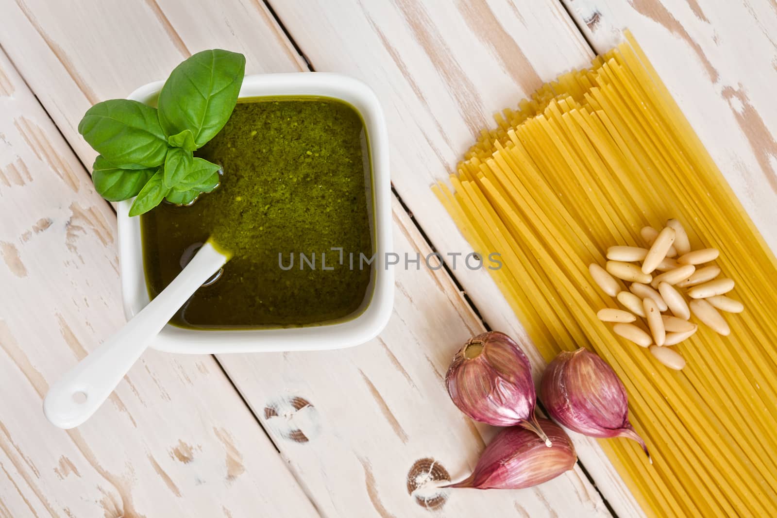 Closeup of pesto genovese and linguine pasta, pine nuts and garlic on a table seen from above