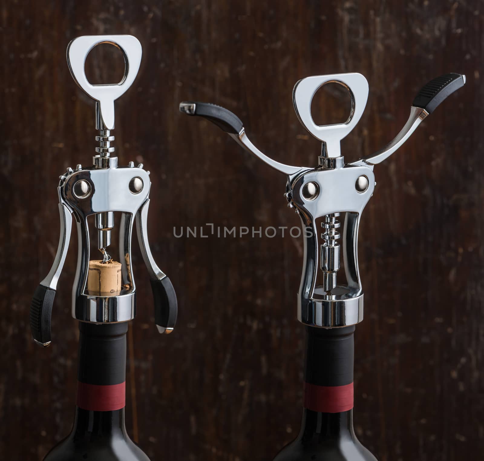 Glossy Metal Wing Corkscrew Opening a Bottle of Wine on Wooden Background. Wine Bottle Opener with Wings Closed and Opened.