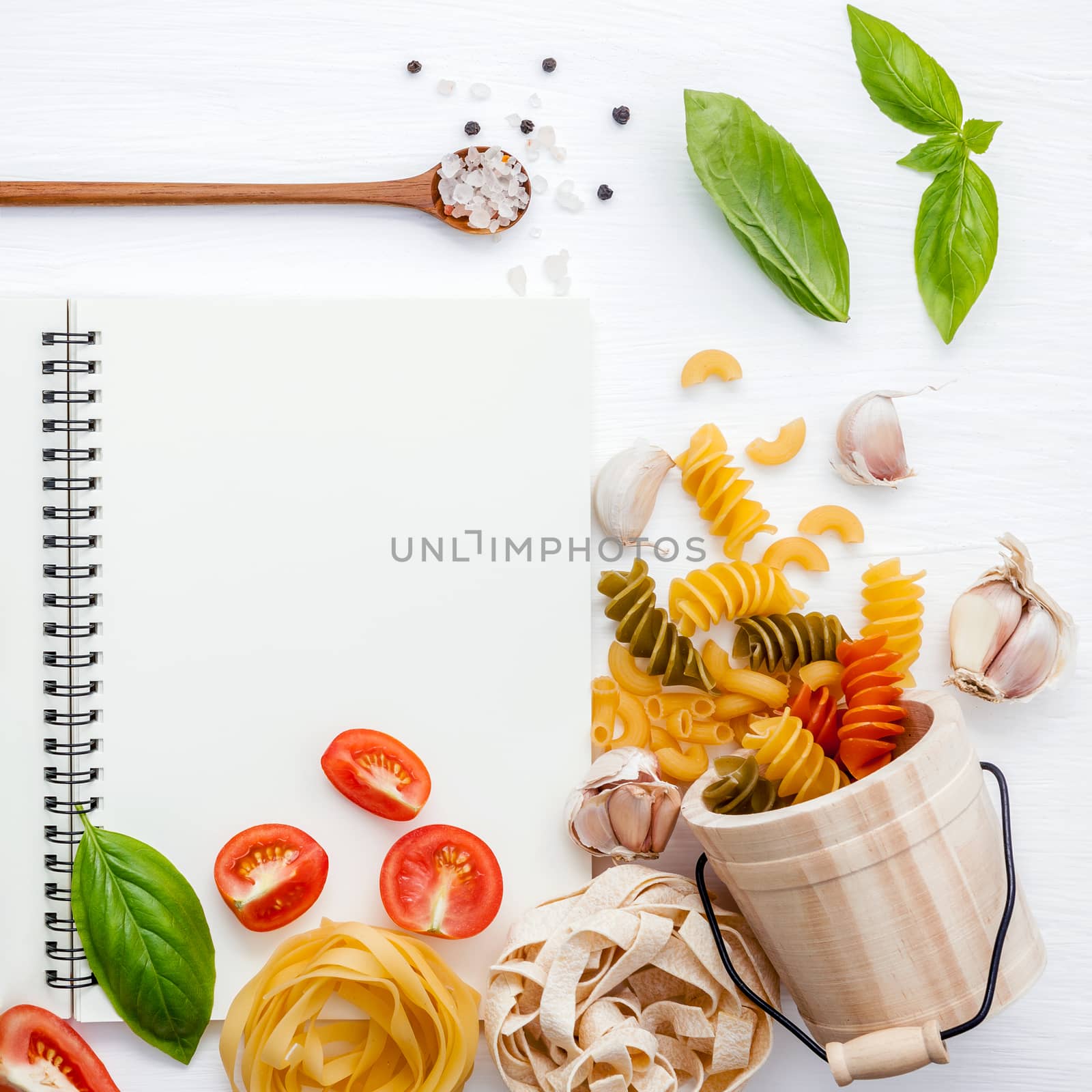 Italian foods concept and menu design . Various pasta elbow macaroni ,fusilli ,fettucini with ingredients sweet basil ,pepper,tomato and garlic setup on white background  flat lay and copy space .