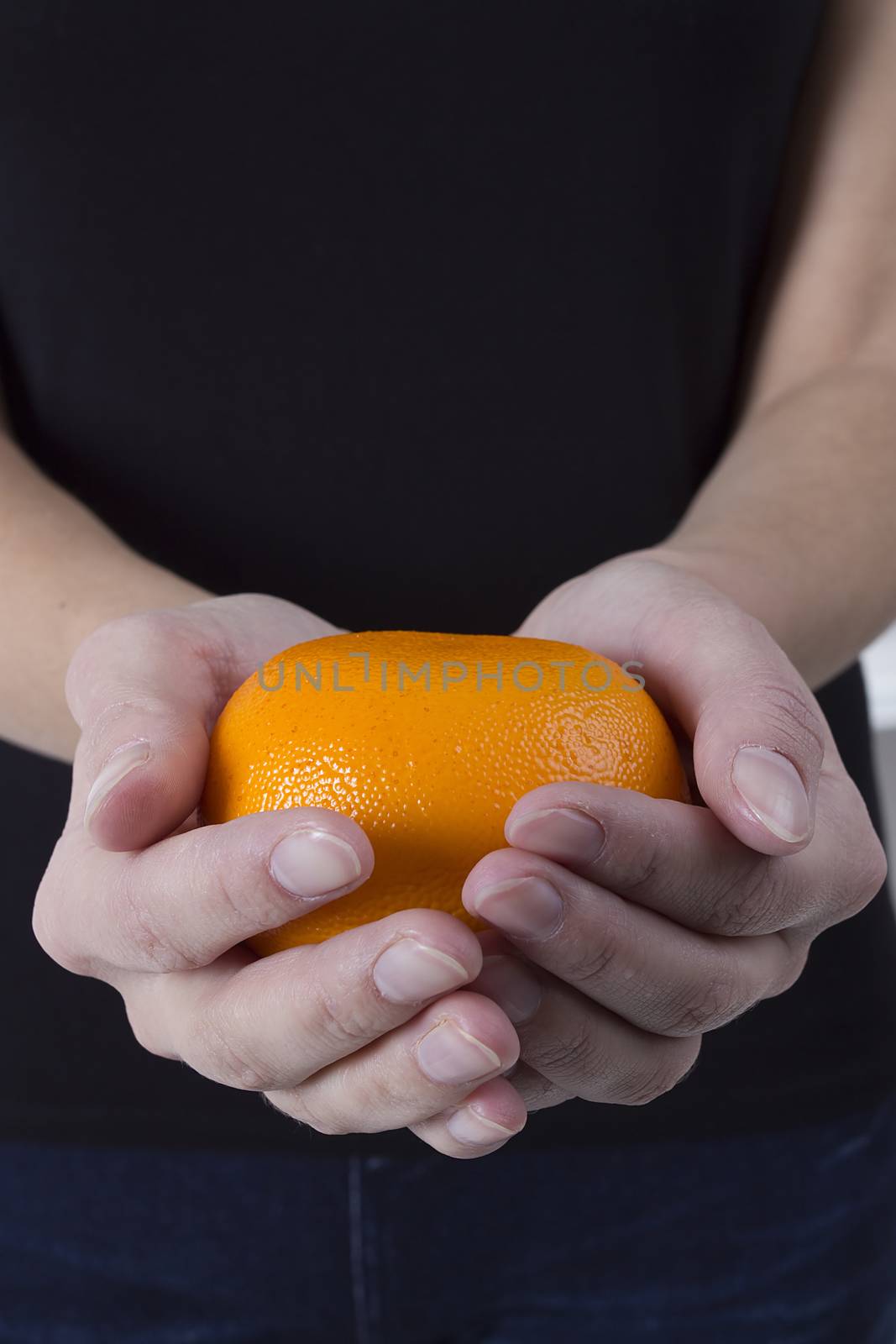 Orange ripe mandarin in the hands of a young woman