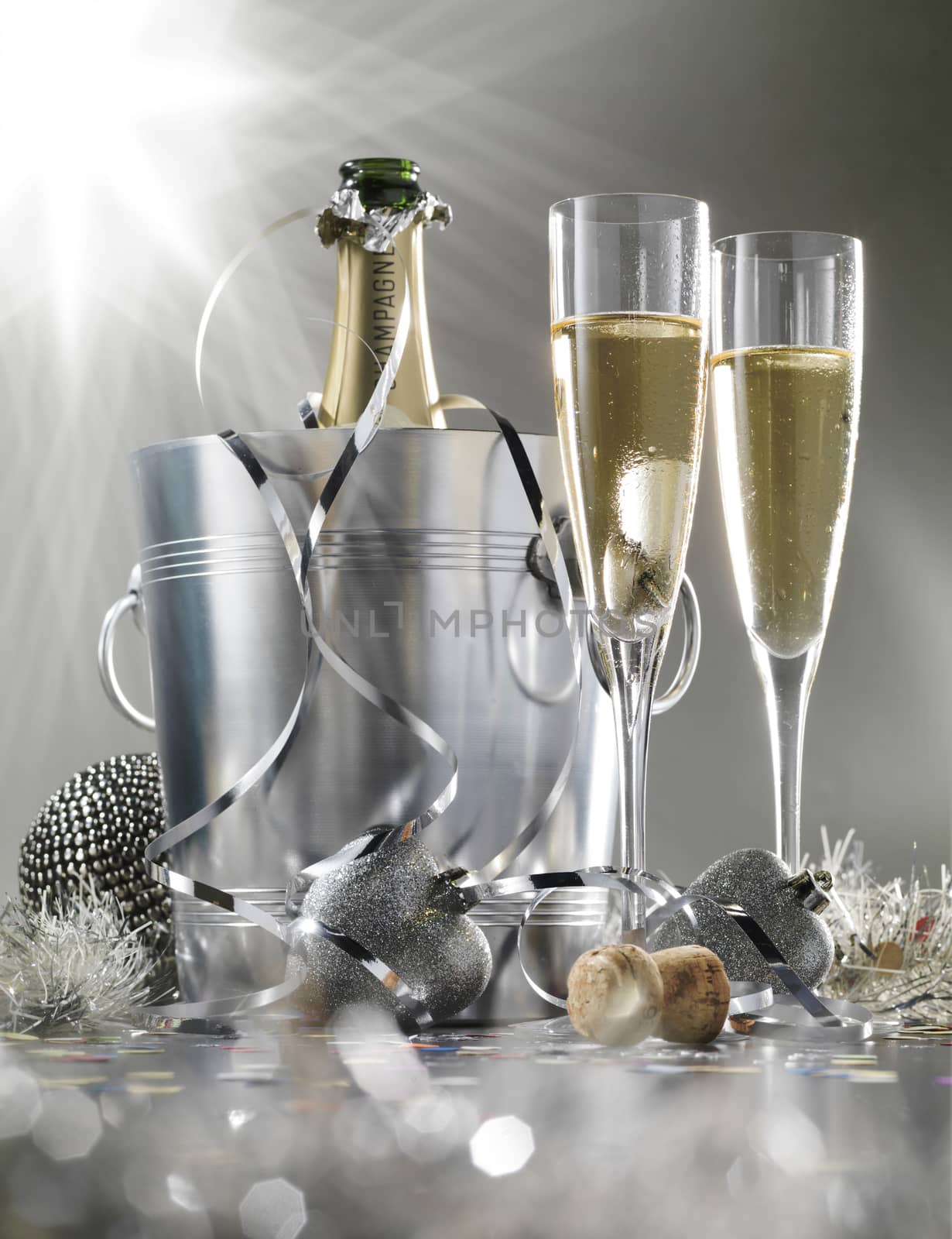 Two glasses of champagne with bottle in cooler on a silver background, selective focus