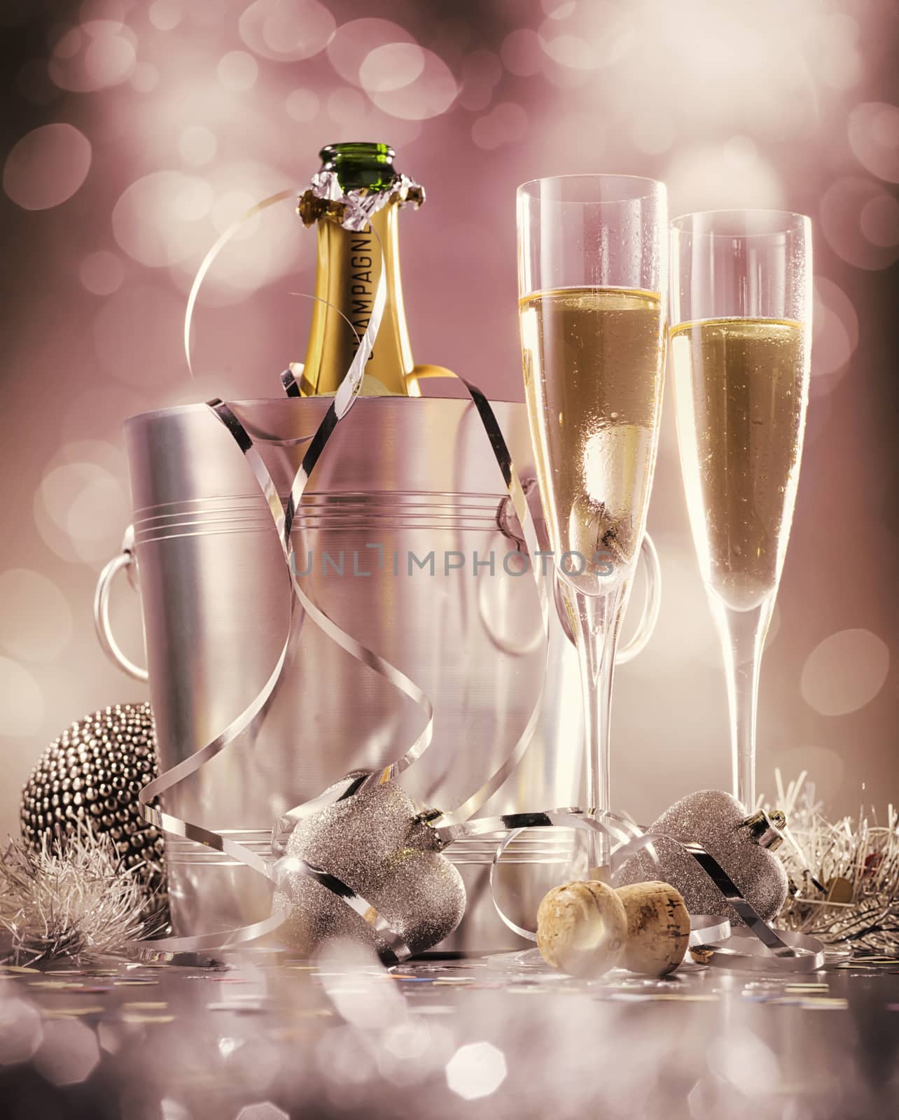 Two glasses of champagne with bottle in cooler on a pink background, selective focus by janssenkruseproductions