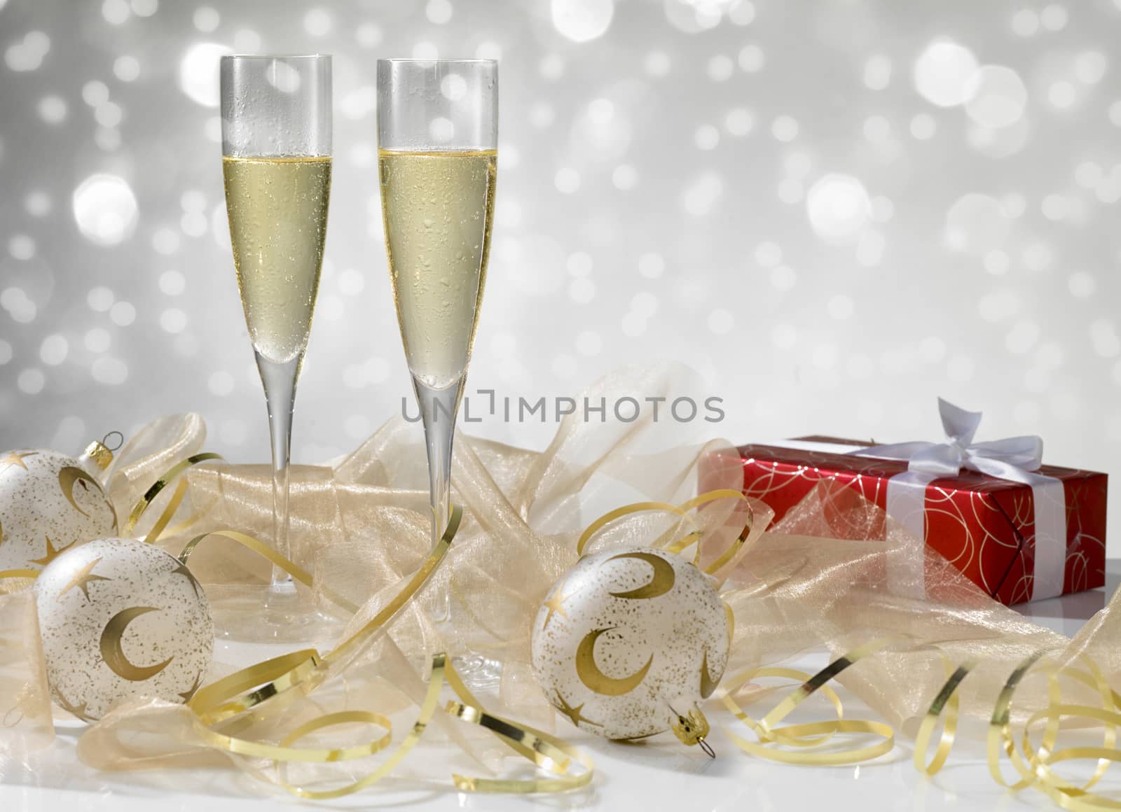 Two champagne glasses, golden decoration. Red gift with white ribbon, stylish tinted by janssenkruseproductions