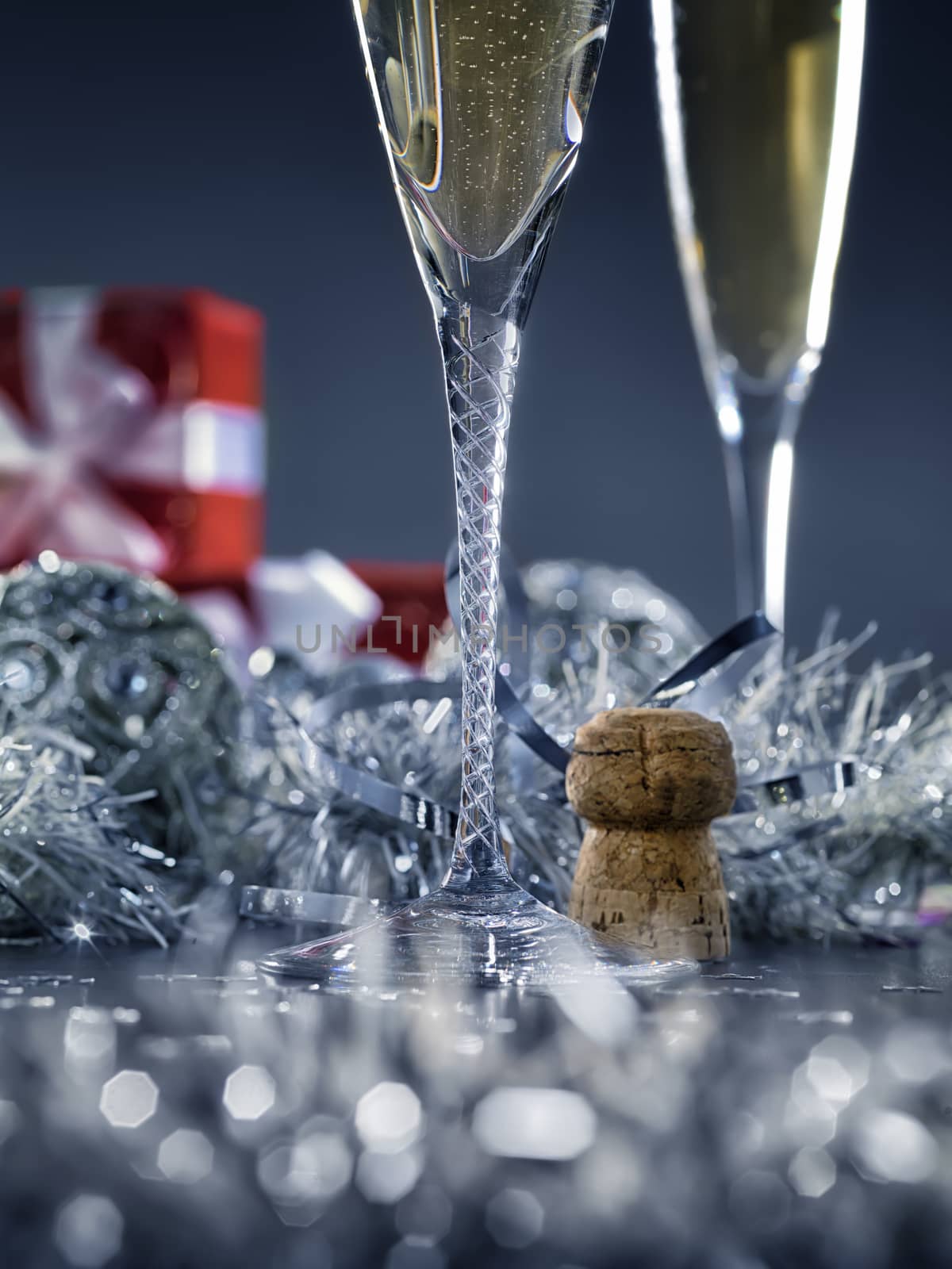 Beautiful silver christmas card with champagne and gifts in the background. Close up.