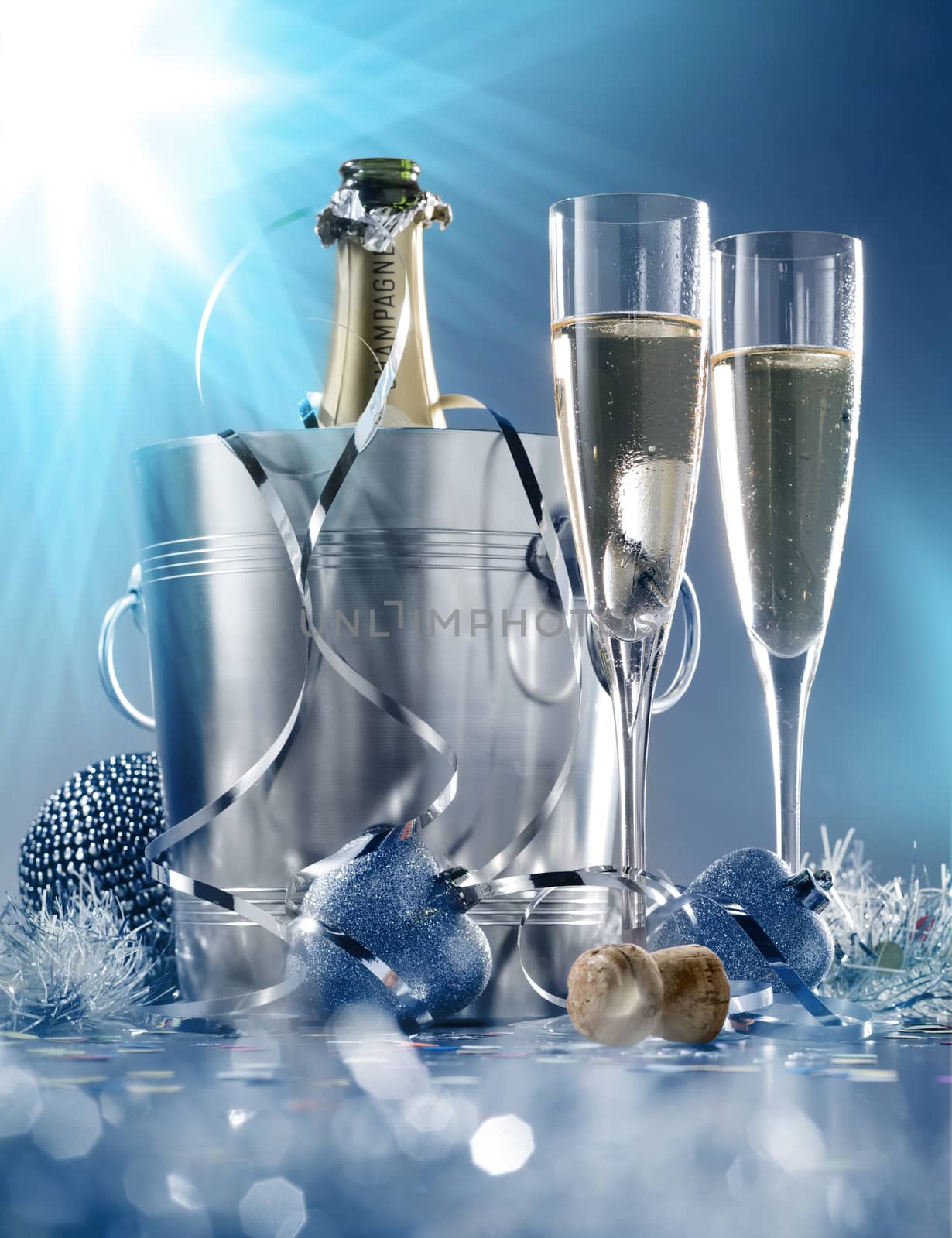 Two glasses and a cooler of champagne on bright blue background by janssenkruseproductions