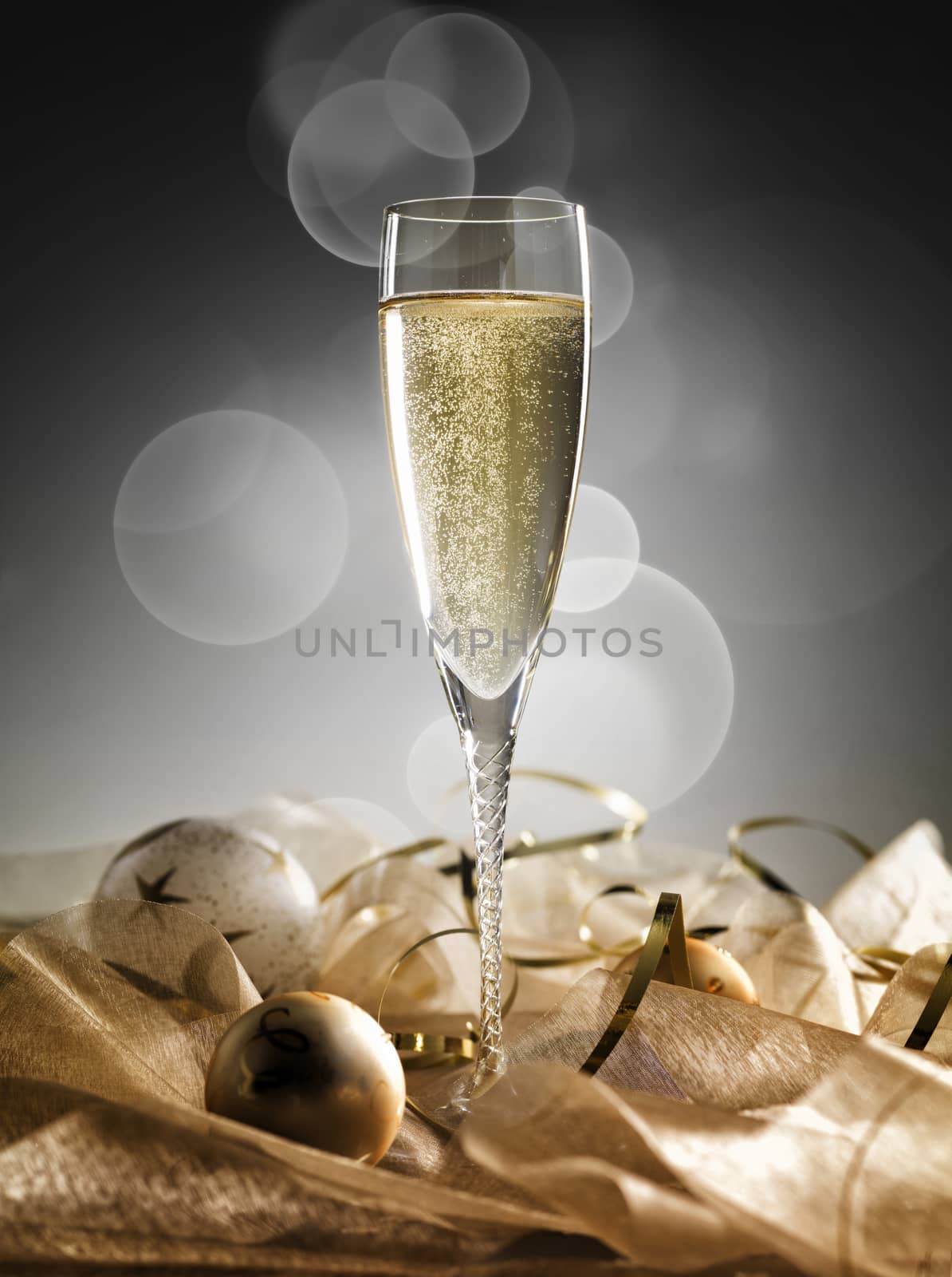 One champagne glass and decoration on golden and silver background by janssenkruseproductions