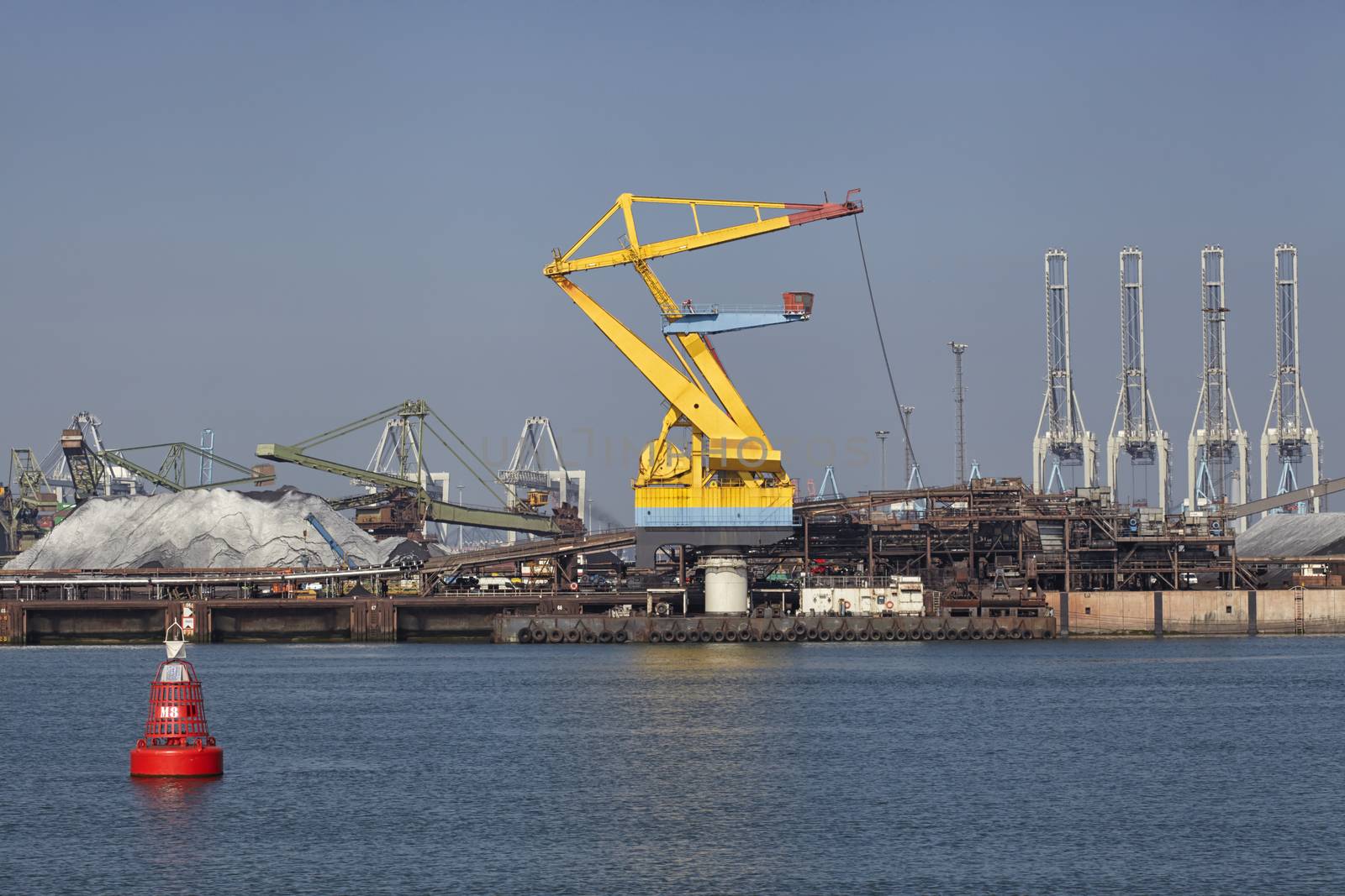 Port cargo crane and sand over blue sky background. Port of Rotterdam.
