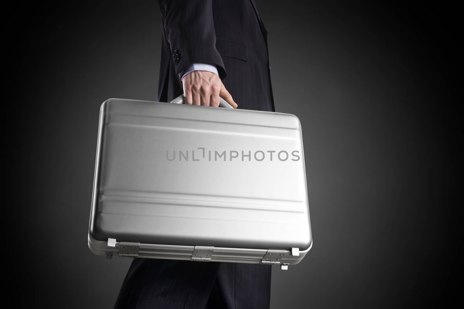 Businessman with a silver suitcase on a dark background with circle gradient by janssenkruseproductions